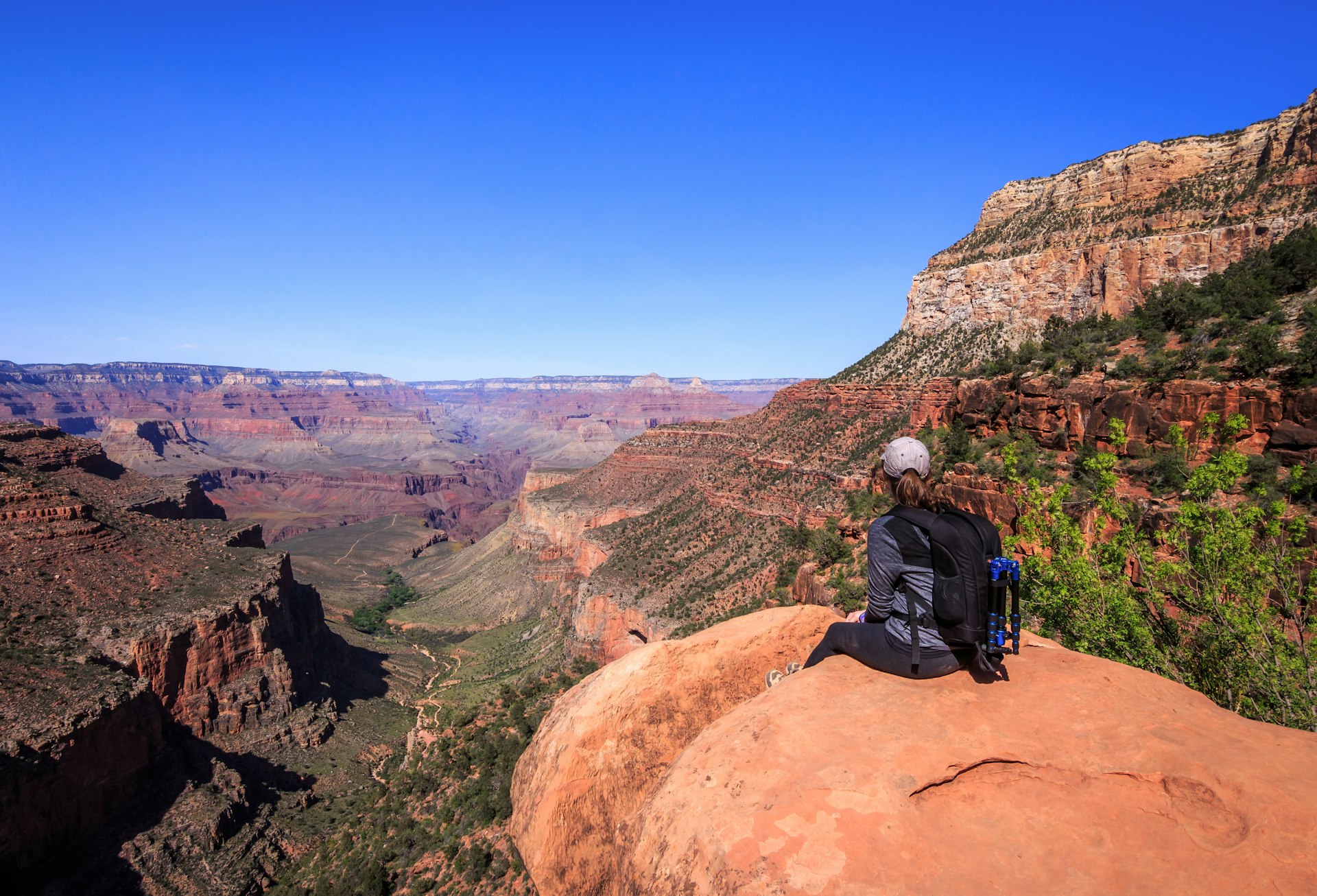 A woman sits on a rock overlooking a deep canyon