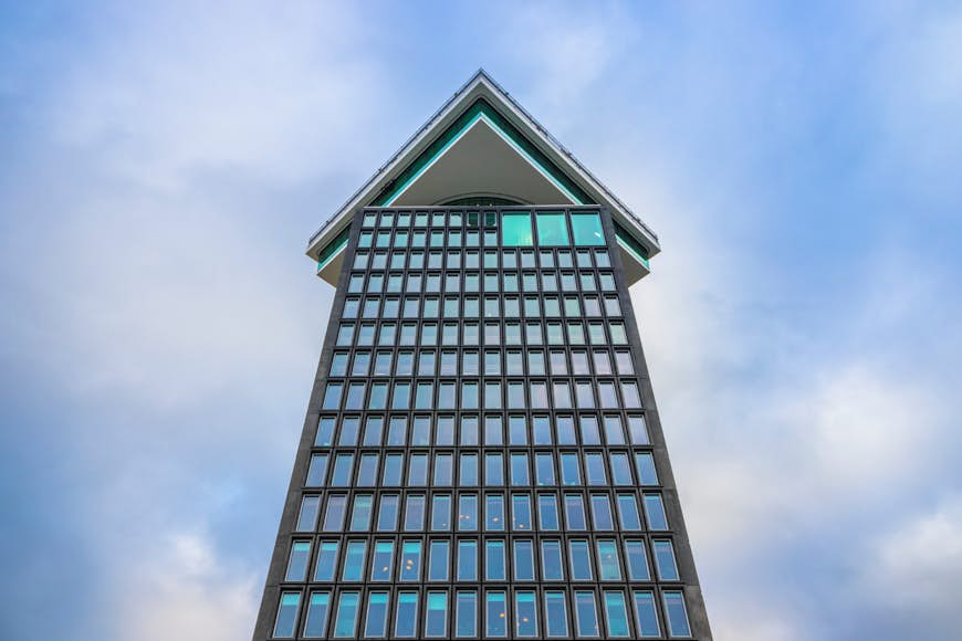 An upwards angle shot to a tall building with the top floor turned 90 degrees to the rest of the building 
