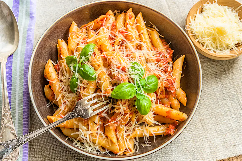 Penne with tomato sauce An overhead shot of a bowl of pasta with thinly grated cheese on top