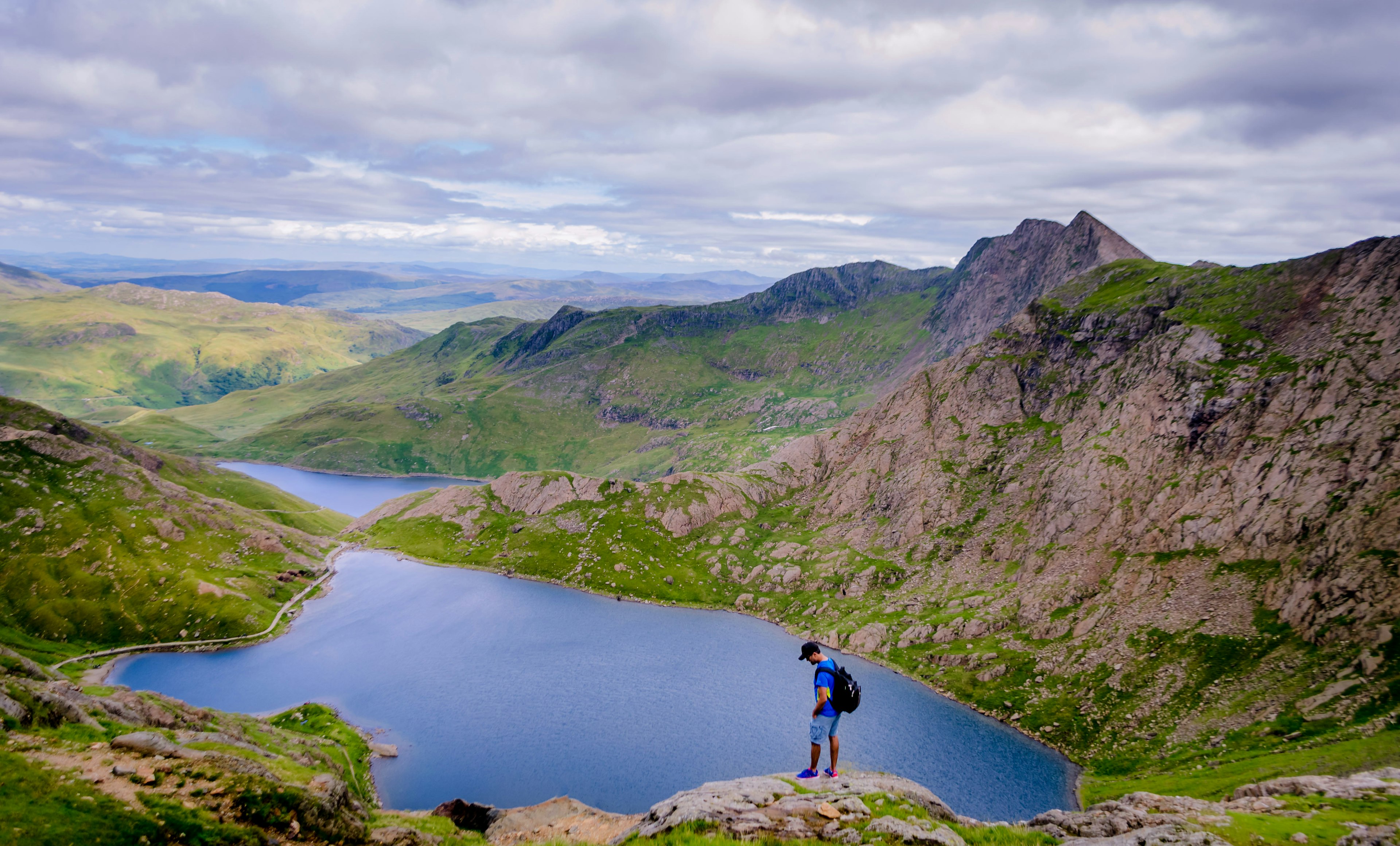 A male hiker standing above Lake Glaslyn on the summit of Snowdon mountain in Wales