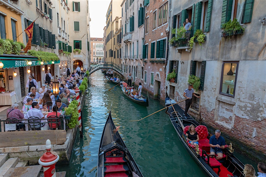 June 30, 2018: A Venice canal with historical buildings and gondolas, as seen from a bridge on a summer evening.