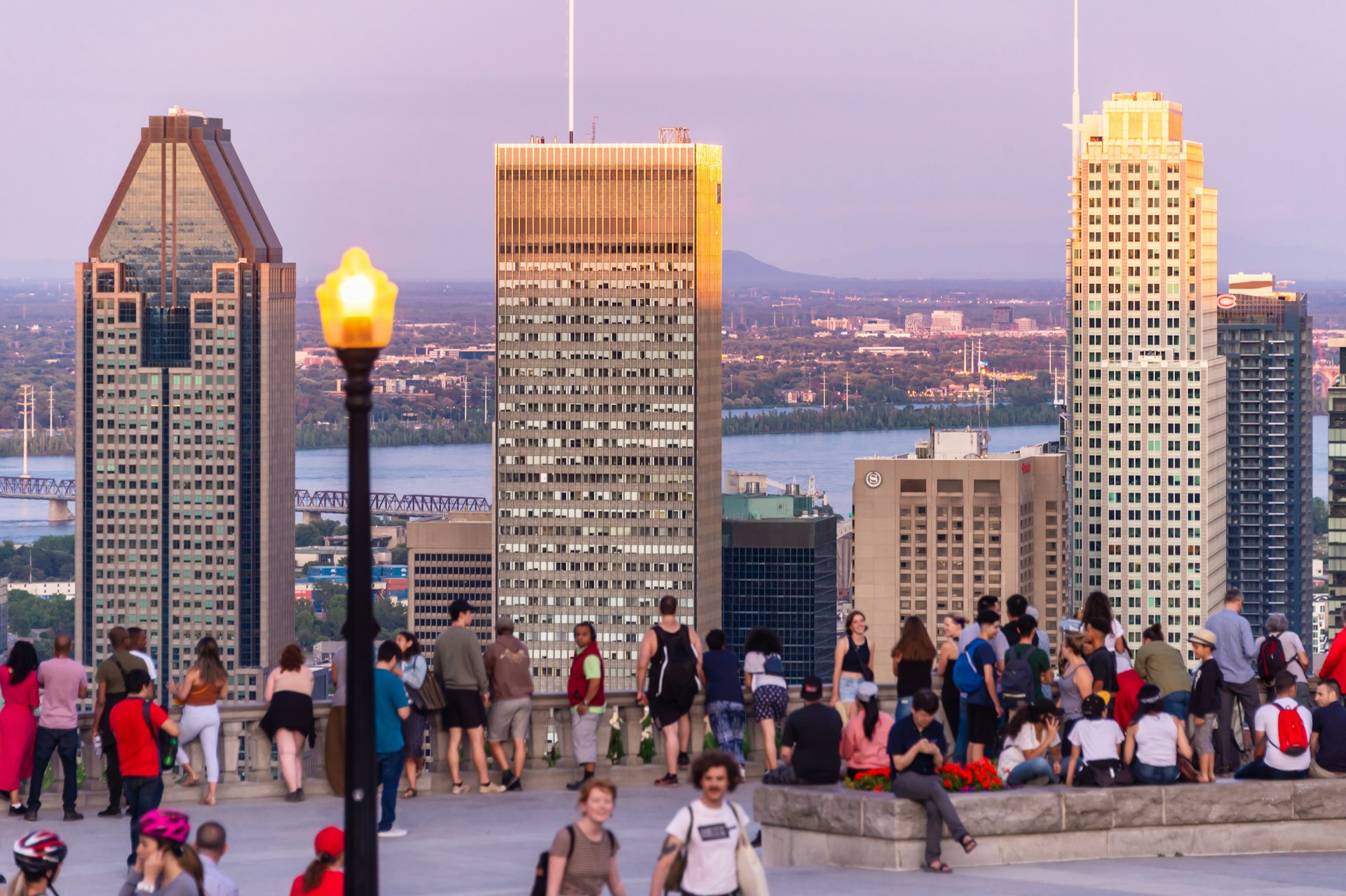 Visitors taking in the view of Montreal skyline from Kondiaronk Belvedere during sunset