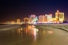 Atlantic City skyline lit up at night, as seen from the beach.