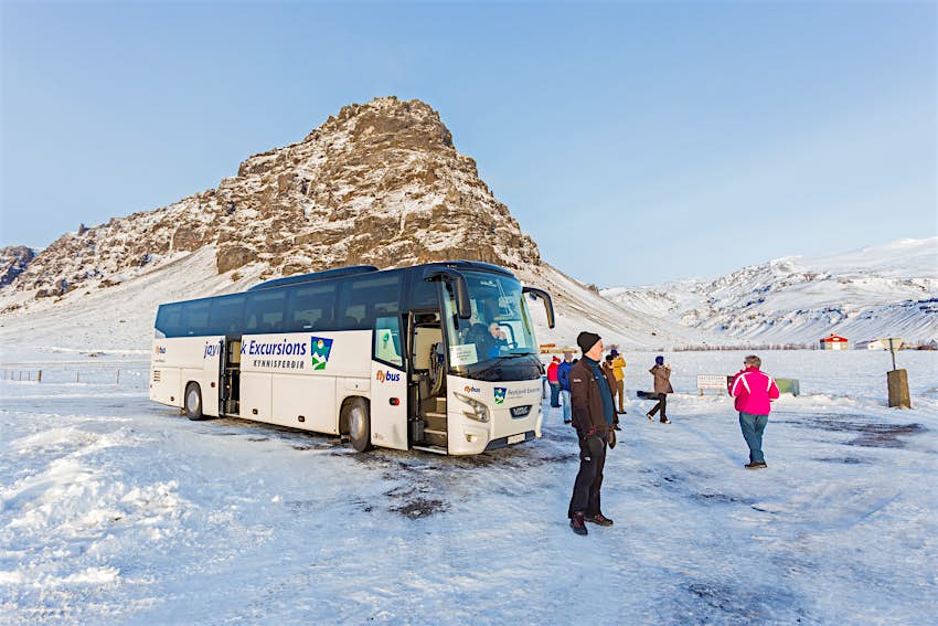 A tour bus parked in front of a snowy mountain