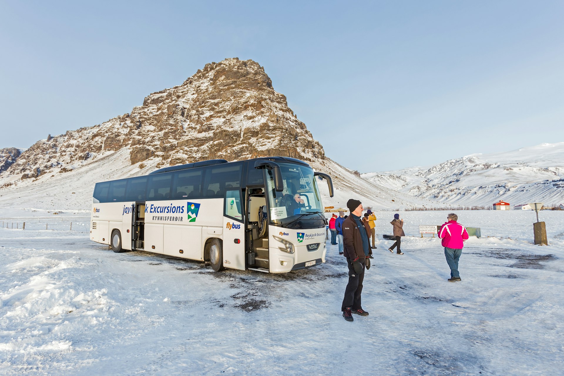 A tour bus parked in front of a snowy mountain