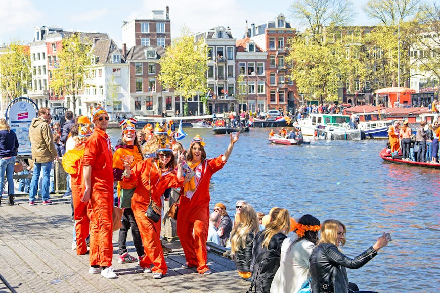 Fester, huvudsakligen klädda i orange, festar vid en kanal
