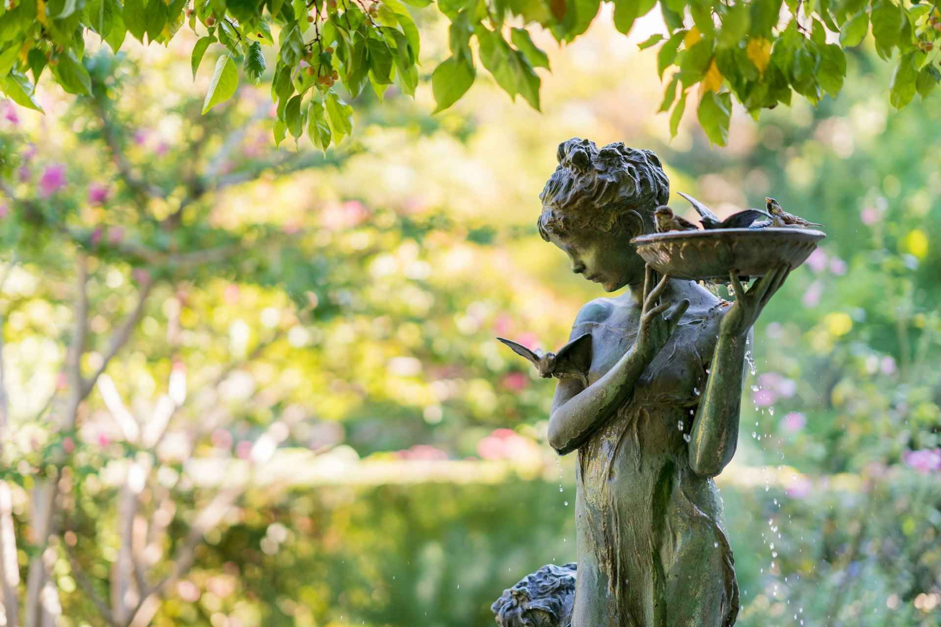 Sculpture of a girl with a bird bath at the Burnett Memorial fountain. Natural setting with a bronze fountain statue in Conservatory Garden, Central Park.