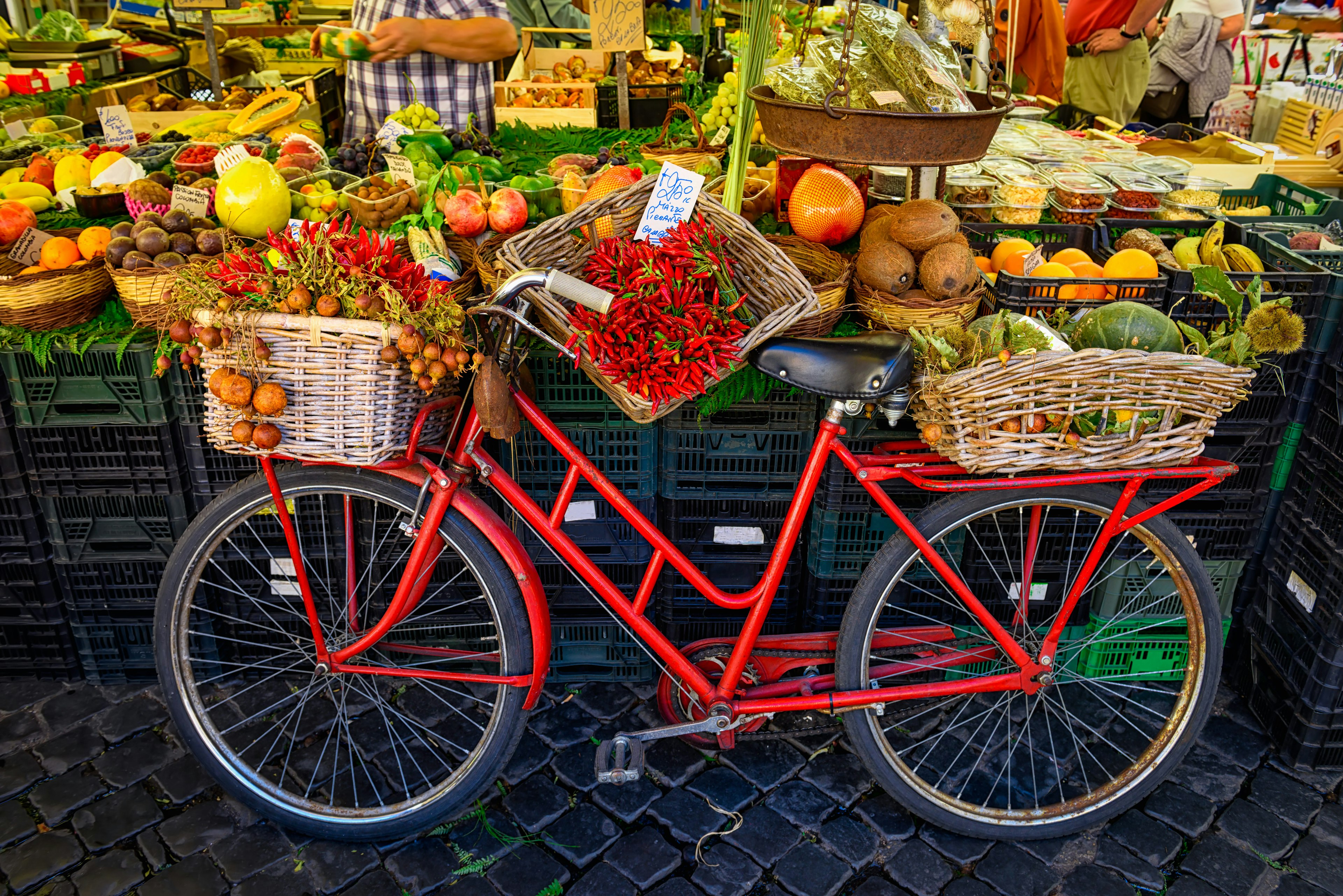 Red vintage bike with fresh produce in baskets at a market on Campo di Fiori.