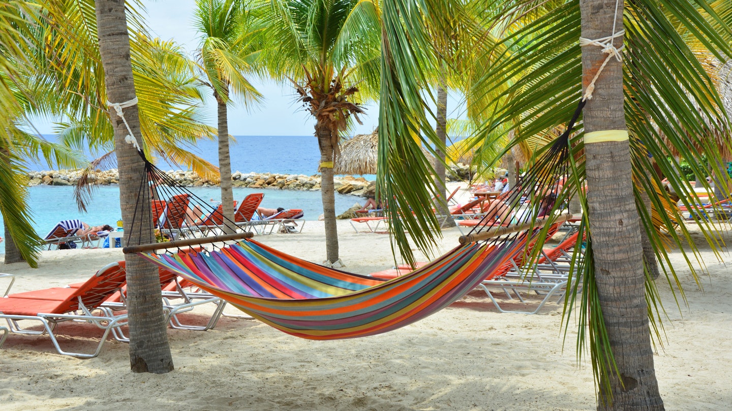 Hammock hanging between palm trees on Curacao beach