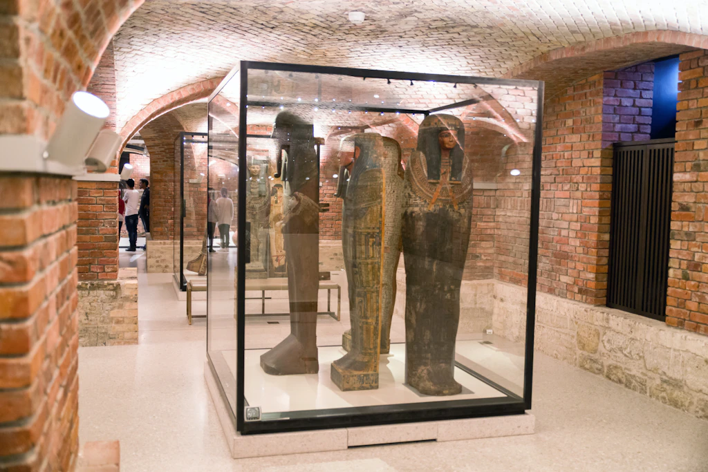 Egyptian Museum, Neues Museum, Berlin A group of sarcophagi stand within a glass display cabinet in a room with arched brick walls