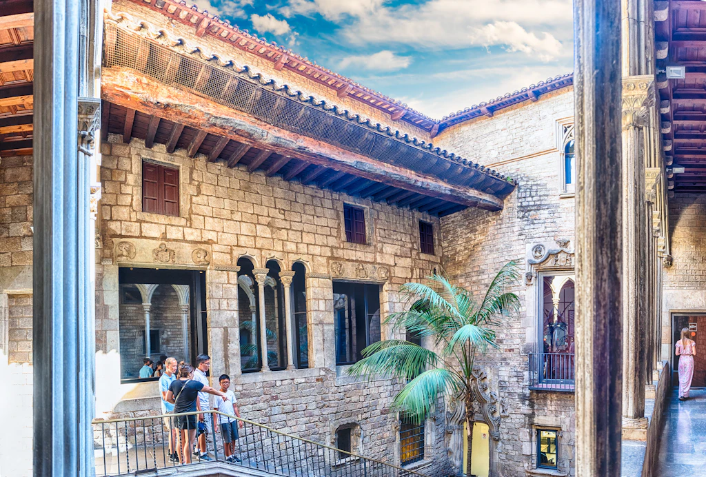 The inner courtyard of Museu Picasso. The square courtyard is spacious, and people walk down a staircase and into it.