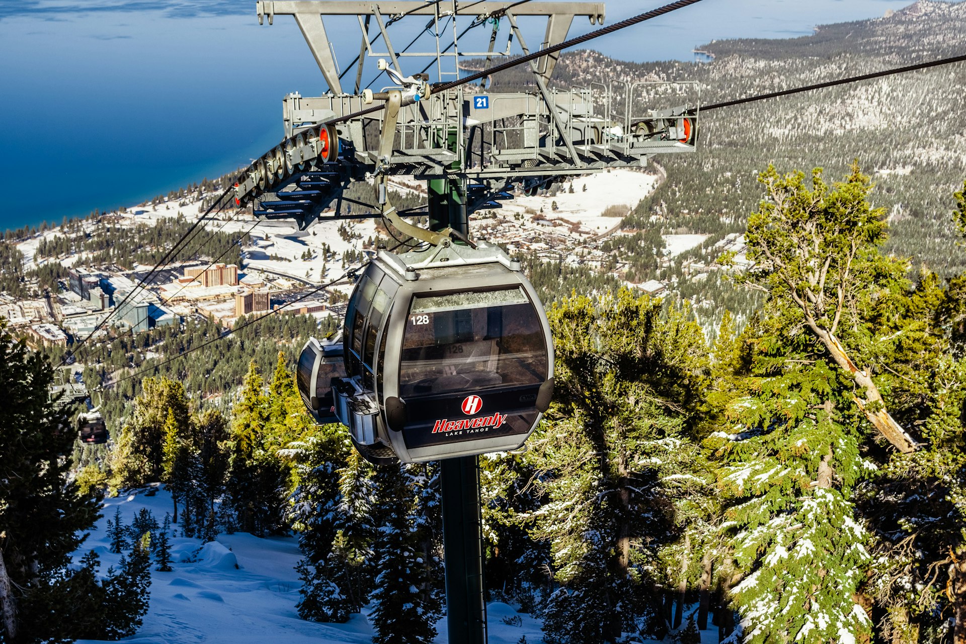 A cable car carriage on its ascent up a mountain. A large lake is in the background