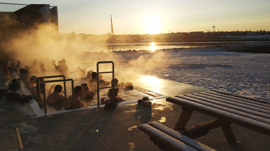 A group of people surrounded by steam in a geothermal pool in Reykjavik, Iceland.