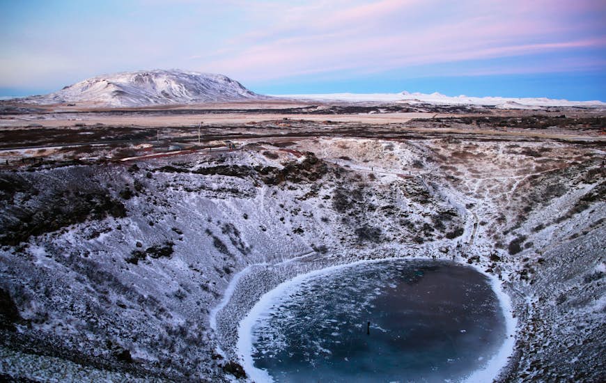 The snow dusted Kerið (Kerid) Crater in Iceland from above with sunset in the distance