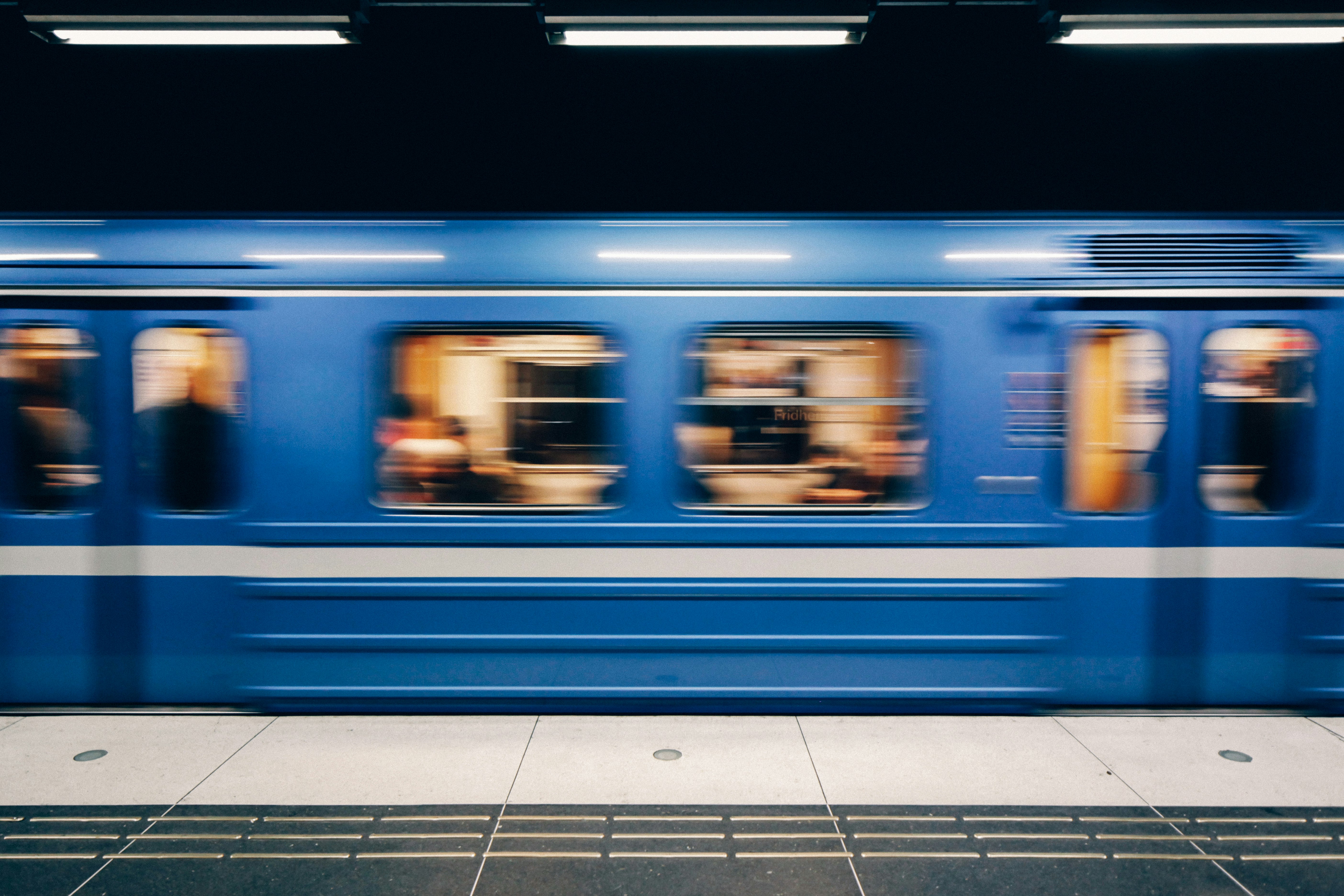 A blue subway train in Stockholm speeds past the platform