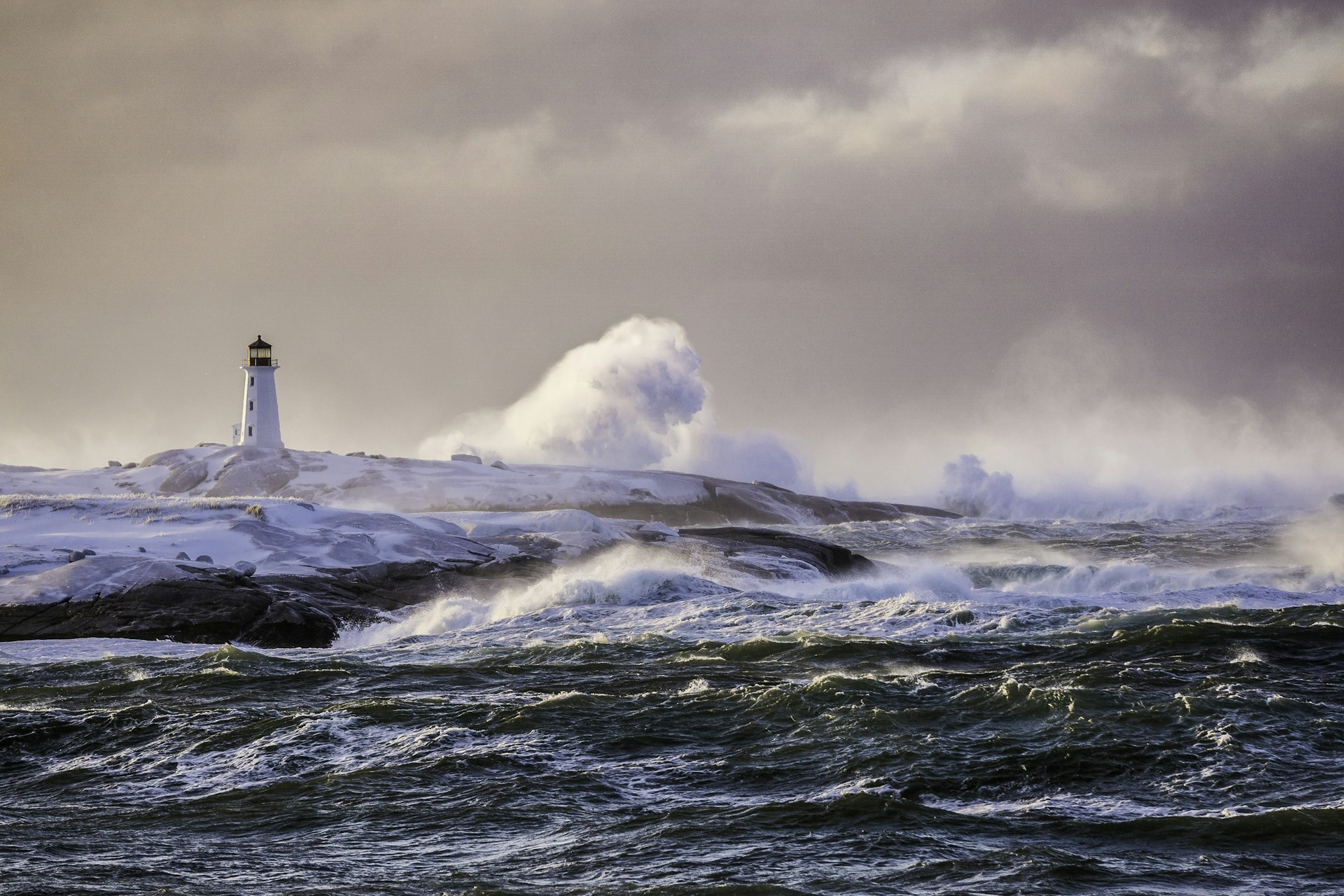 Lighthouse at Peggy's Cove being buffeted by winter storm ocean waves.