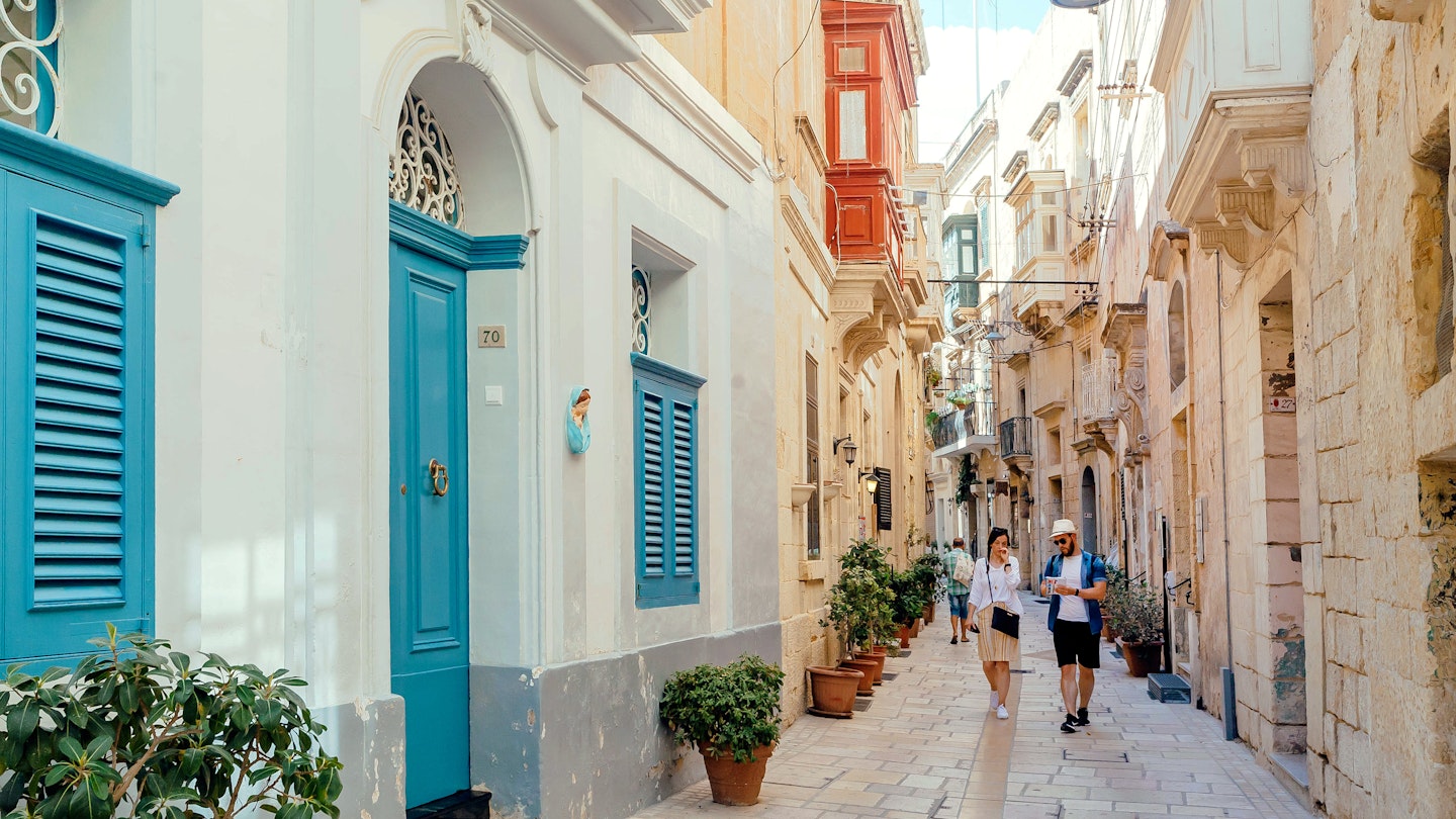 Birgu, Malta: Tourists walking down narrow streets with wooden doors and historical houses on 28 September, 2019. Birgu, also known as Vittoriosa has population near 4,000