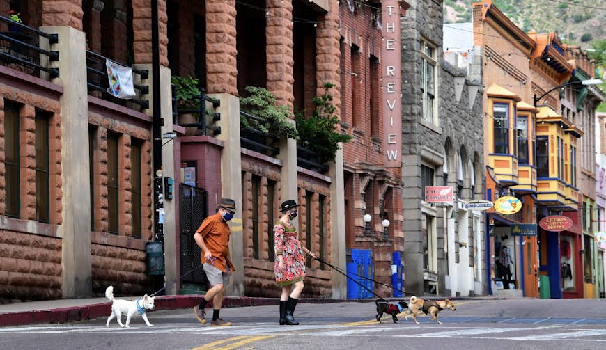 A man and a woman walk their dogs across a quiet Main Street in Bisbee, Arizona