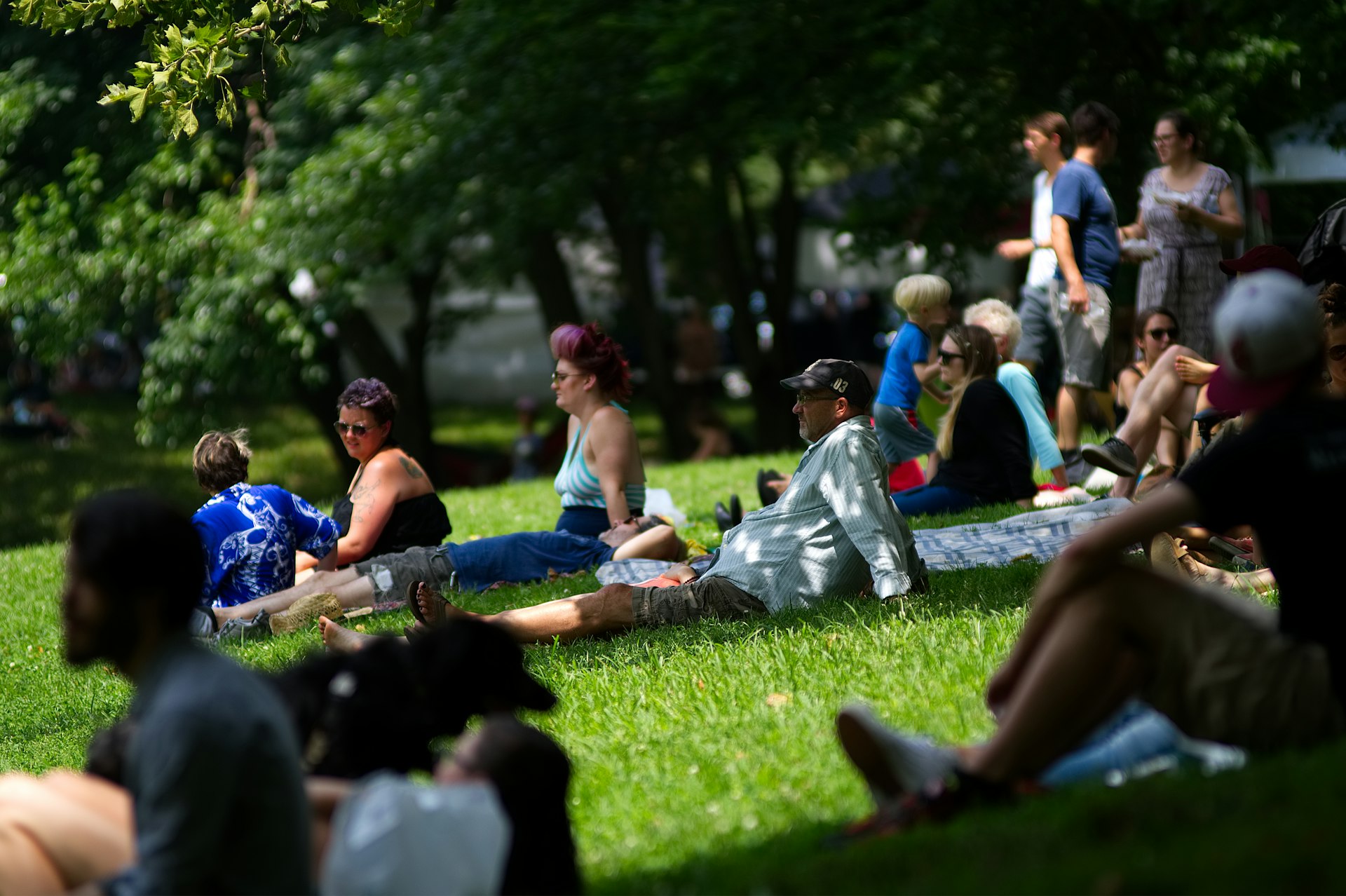 eople sit on the grass at an annual community festival as local bands perform and arts, crafts and food vendors line pathways in a park in the West Philadelphia neighborhood, in Philadelphia, PA.