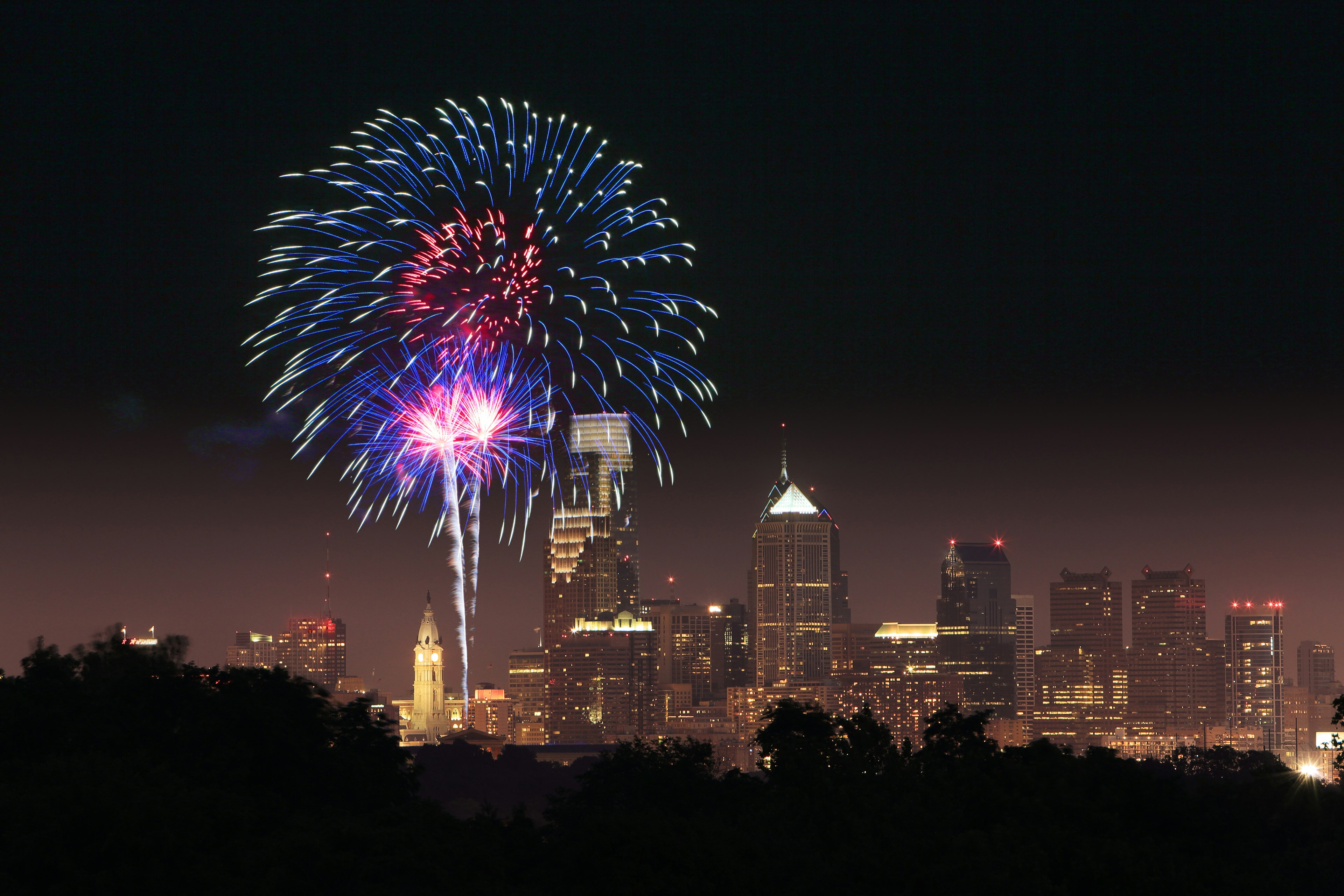 Fireworks exploded over a body of water with the Philadelphia skyline in the background.