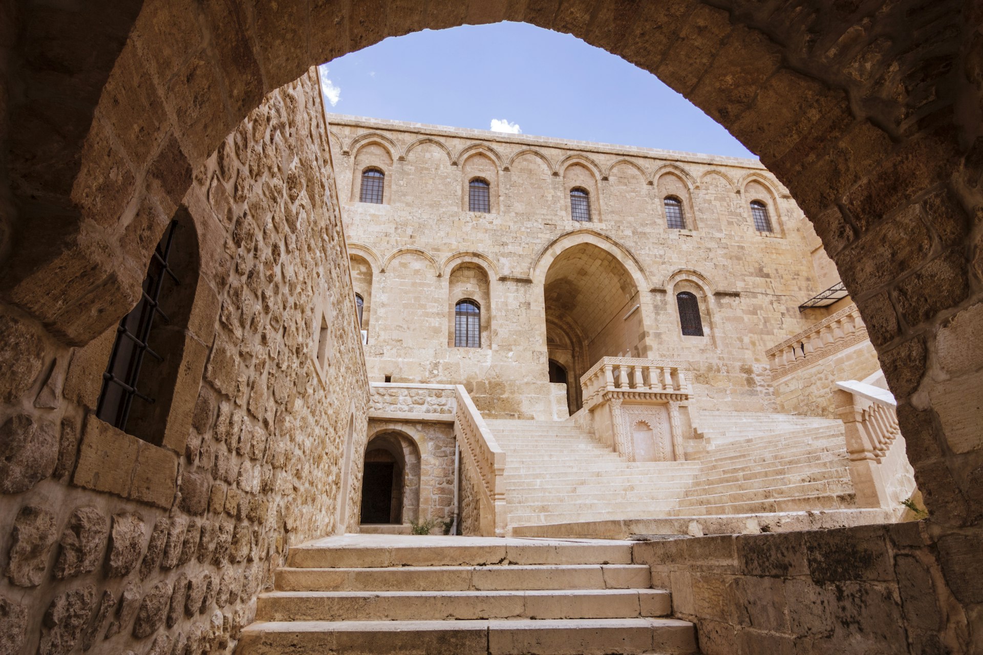 A sandstone-colored monastery building viewed through an archway