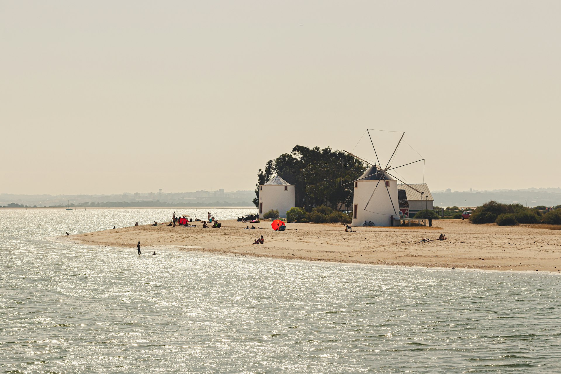 Two white stone round windmills on a sandy beach