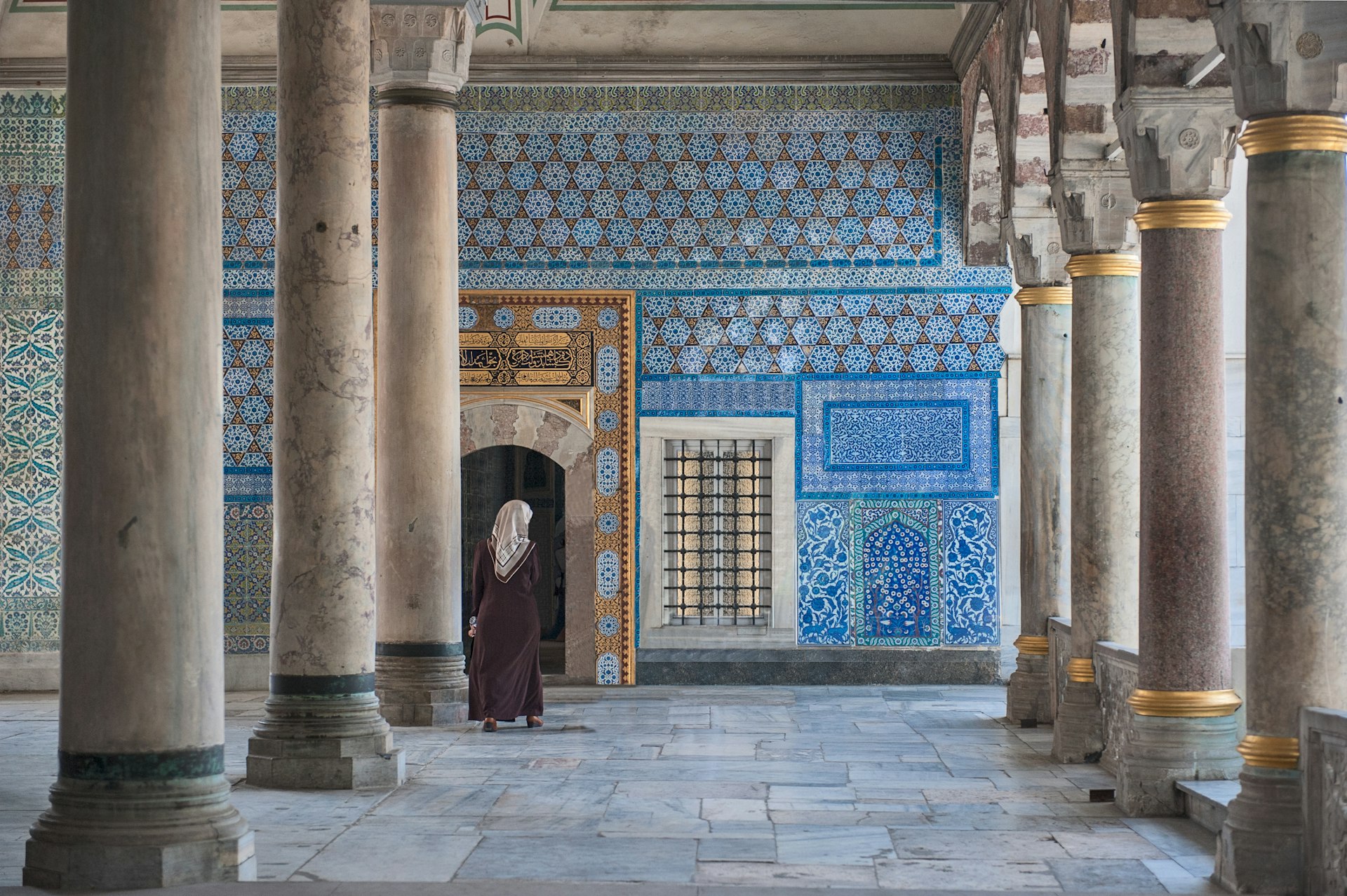 Woman walking by the ornate tiled interior of Topkapi Palace, Istanbul