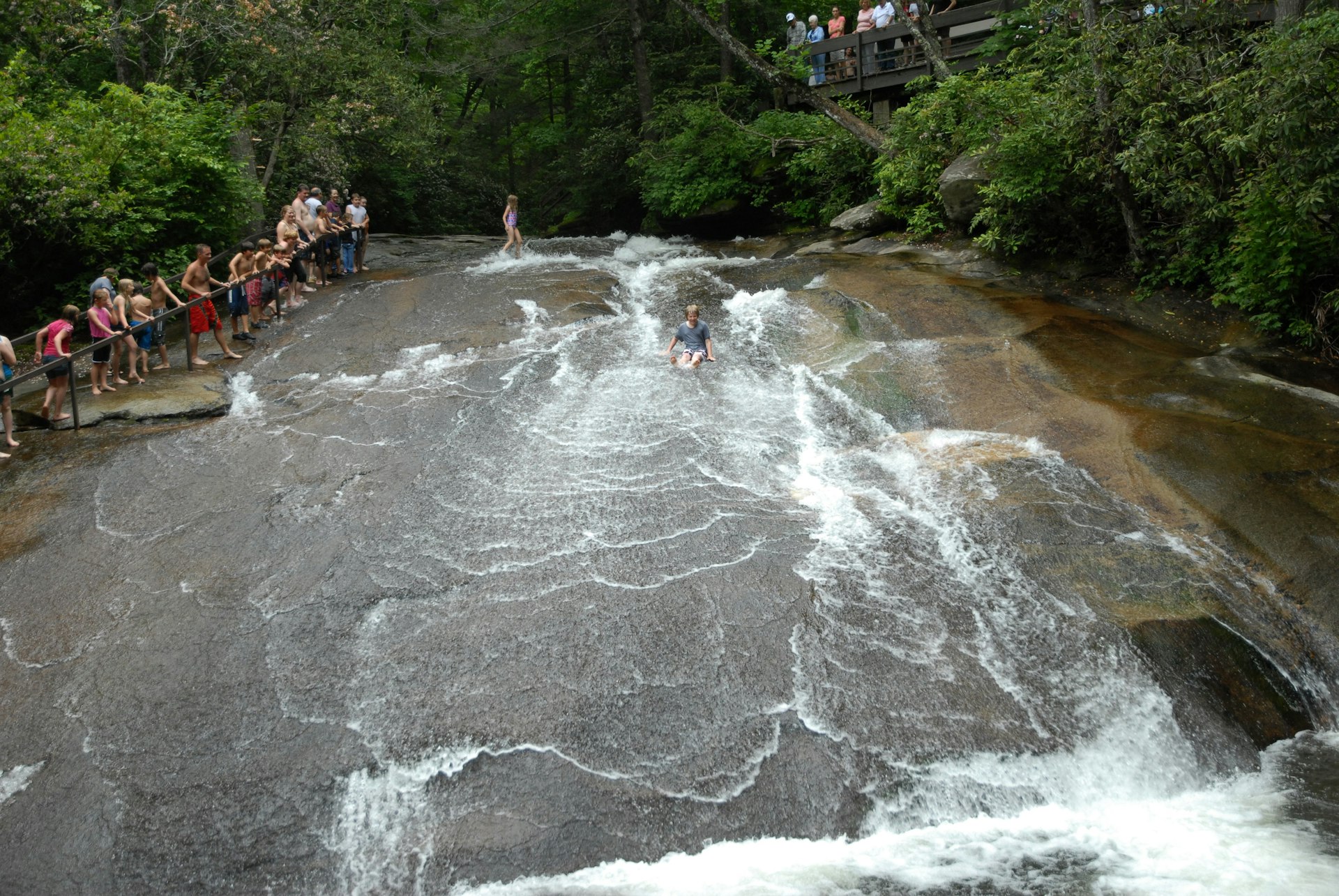 Kid sliding down the natural rock waterfall at Flat Rock, North Carolina