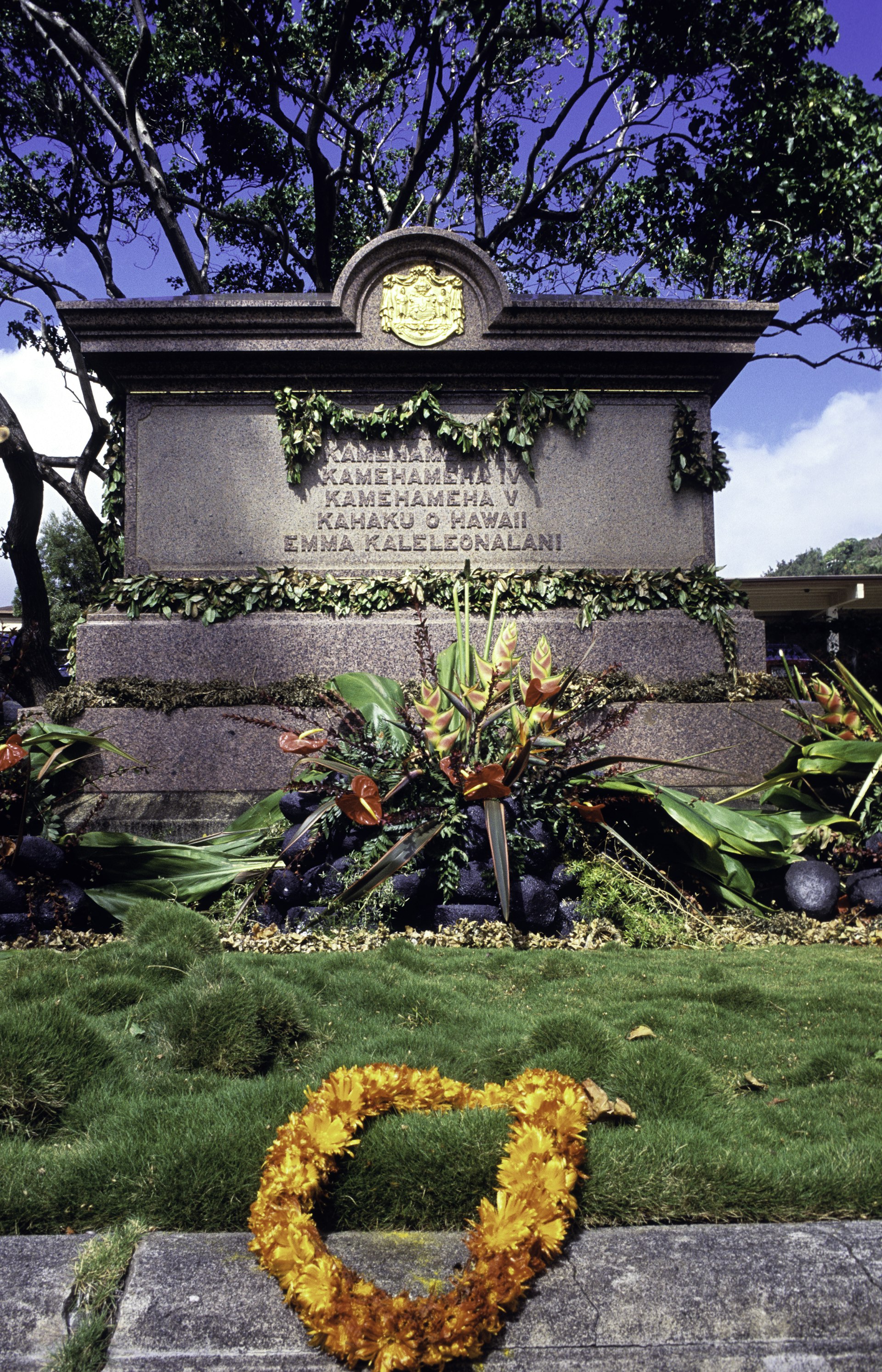 A large tomb with names of royalty engraved on it, and a ring of orange flowers at its base