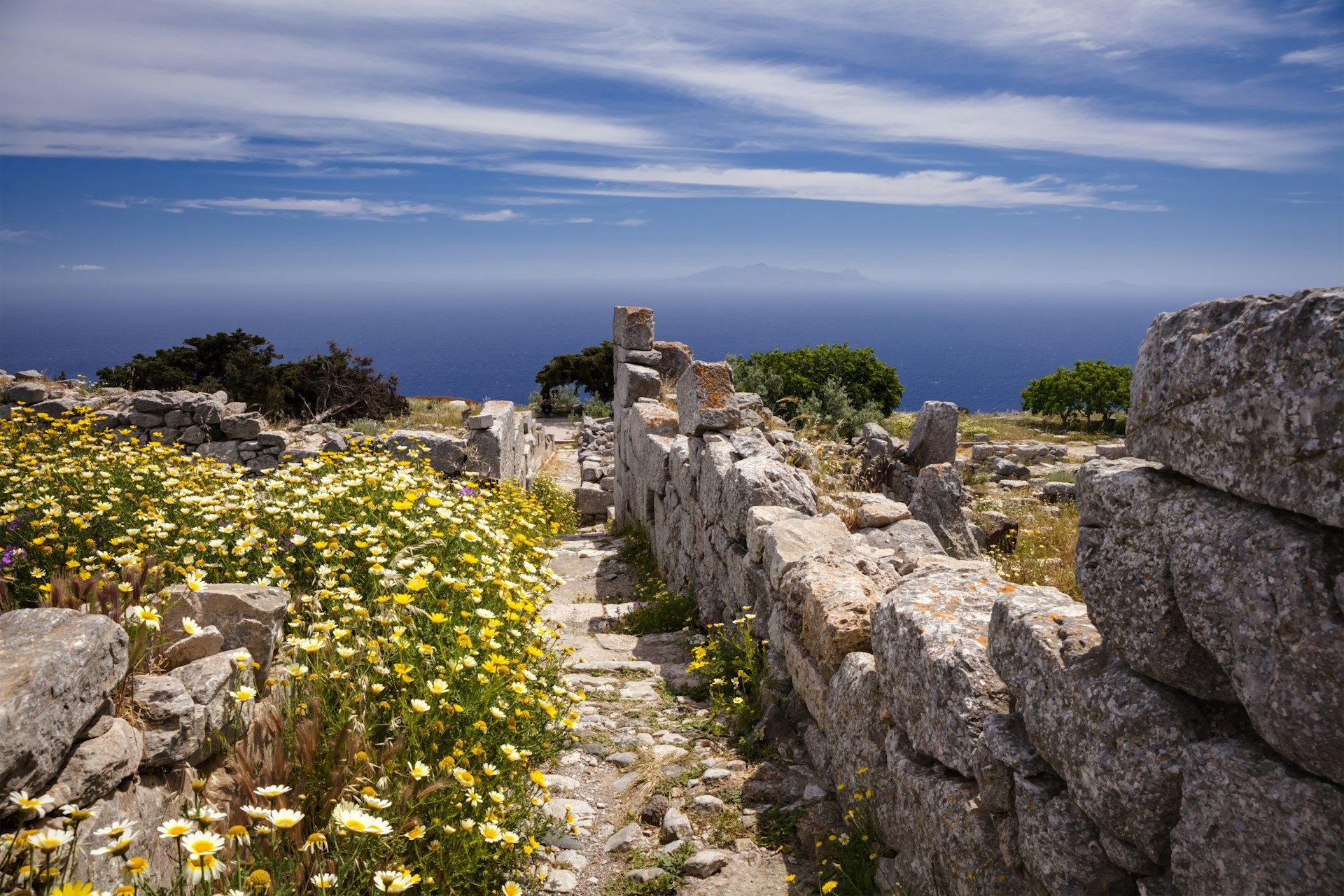 An ancient clifftop settlement with stone walls lined with wildflowers