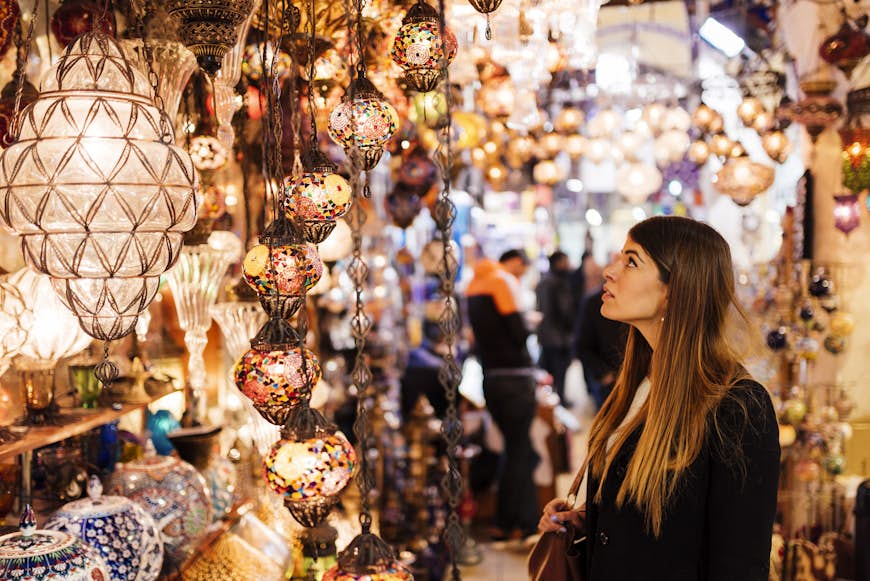 Ung kvinna tittar på lampor på ett marknadsstånd i basardistriktet i Istanbul, Turkiet