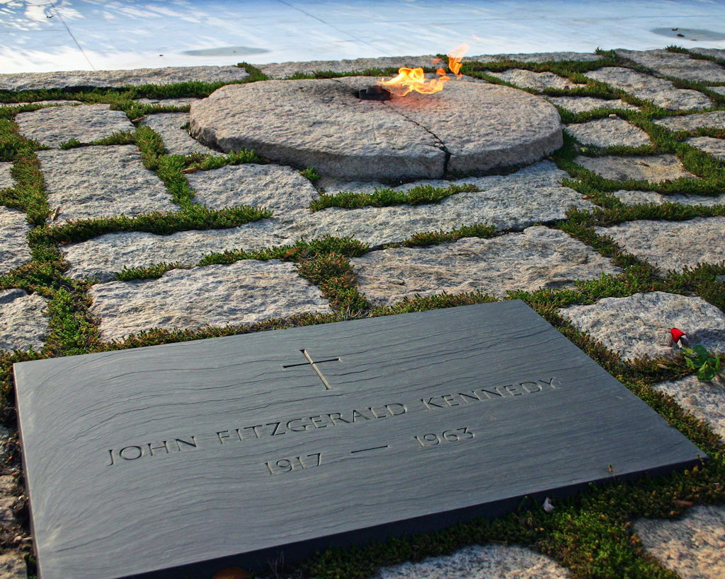 JFK Memorial at Arlington National Cemetery A black slab of stone with 'John Fitzgerald Kennedy' on it and the eternal flame in the background
