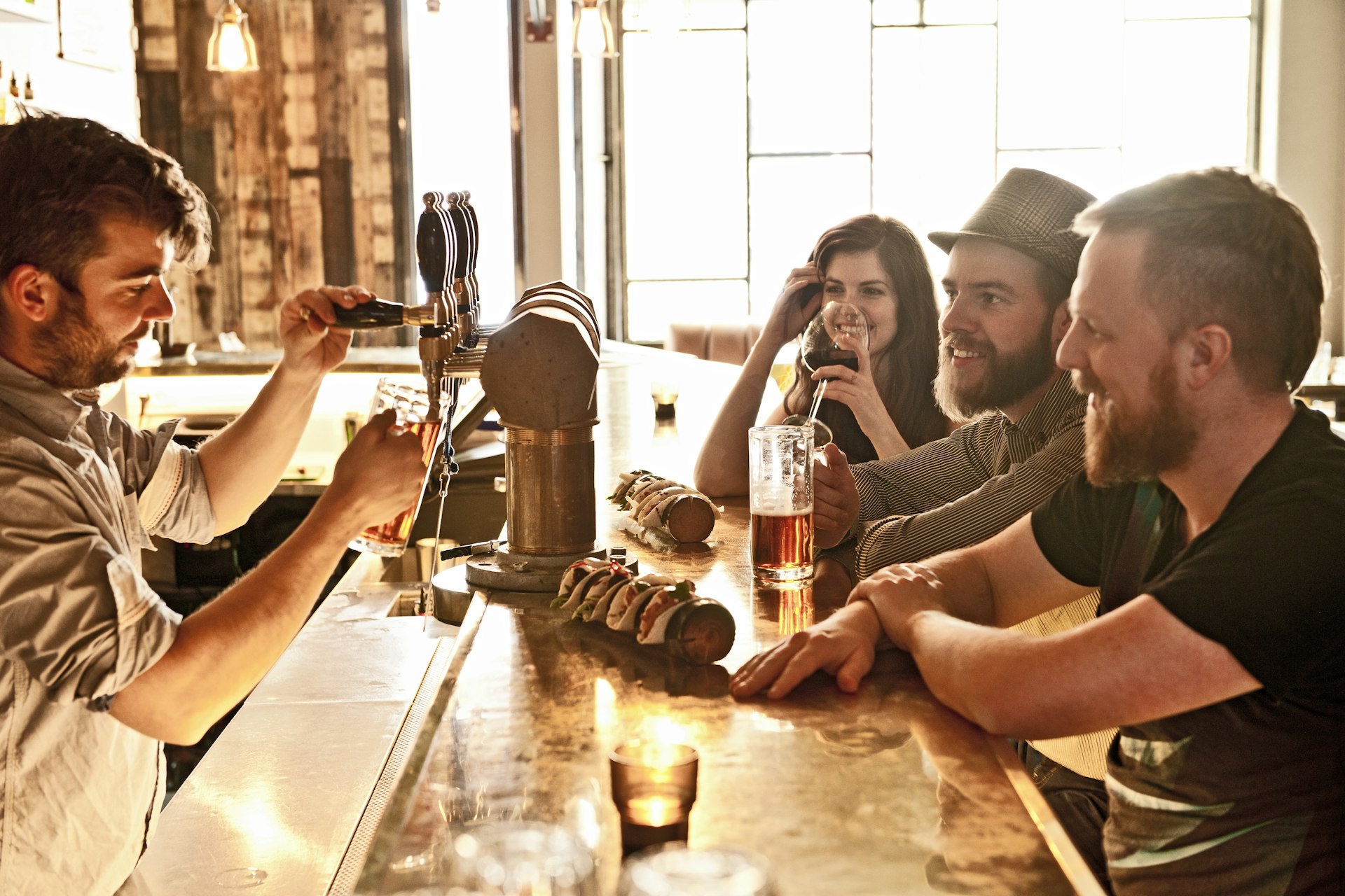 Friends drinking beer at hipster bar in Reykjavík in a cool afternoon with the sunshine beaming in