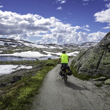 Norway, summer 2014. Young man bicycles Rallarvegen, that runs between Haugastøl and Flåm. Hardangervidda National Park. Beautiful scenery with small lakes and high mountains.