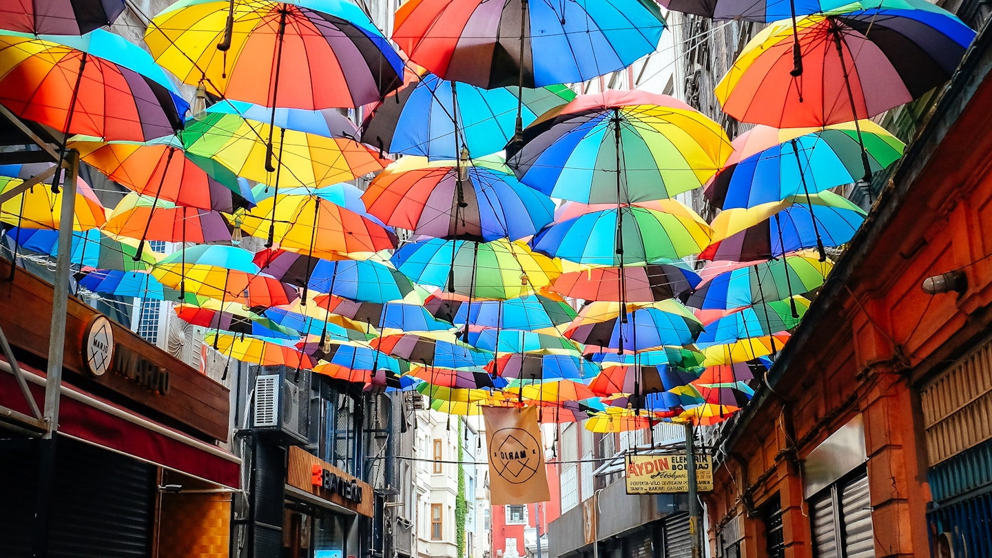 April 24, 2017: Man walking along a street that has been decorated with colourful umbrellas in the hip district of Karakoy.