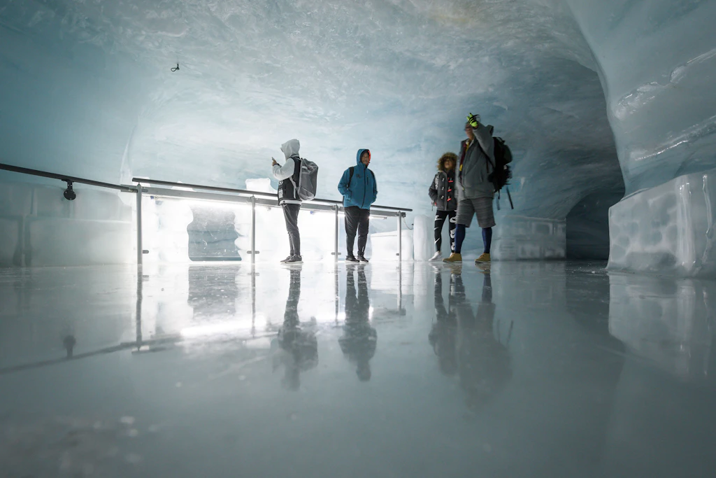 People walk around the Ice Palace at Jungfraujoch, an underground facility where the walls, floors and ceilings are made of thick white ice.