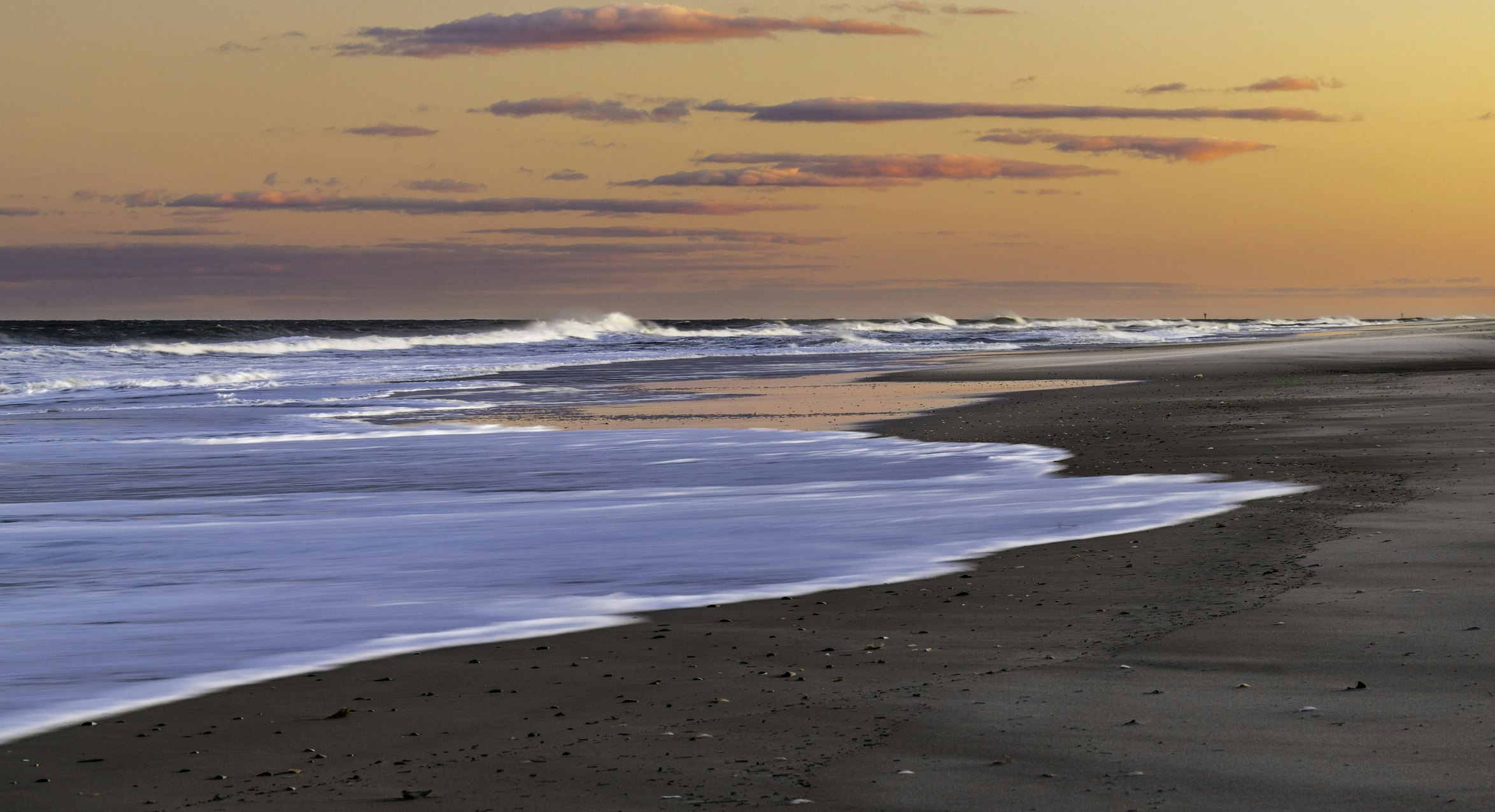 Waves crash on the beach of Island Beach State Park New Jersey as the sun sets