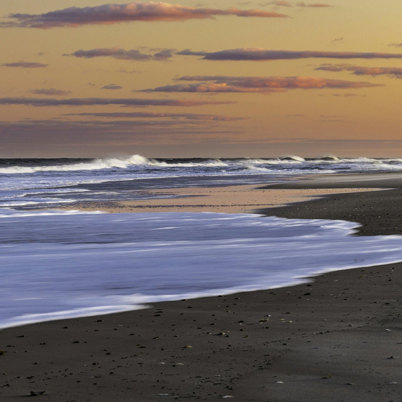 Waves crash on the beach of Island Beach State Park New Jersey as the sun sets