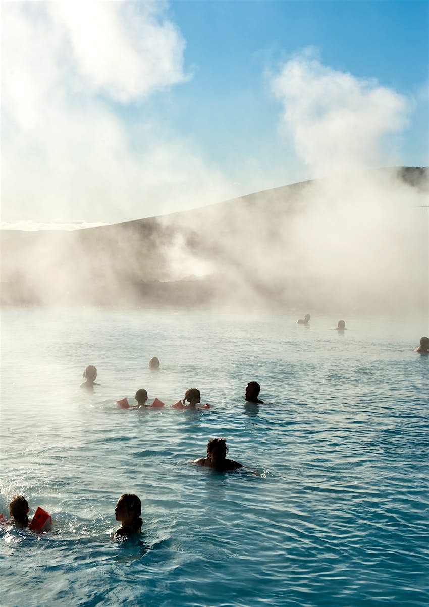 People bathe in the Jarðböðin Nature Baths, a natural hotspring bath near Myvatn in north Iceland. Steam is coming from the geothermal pool, which has inviting blue waters.