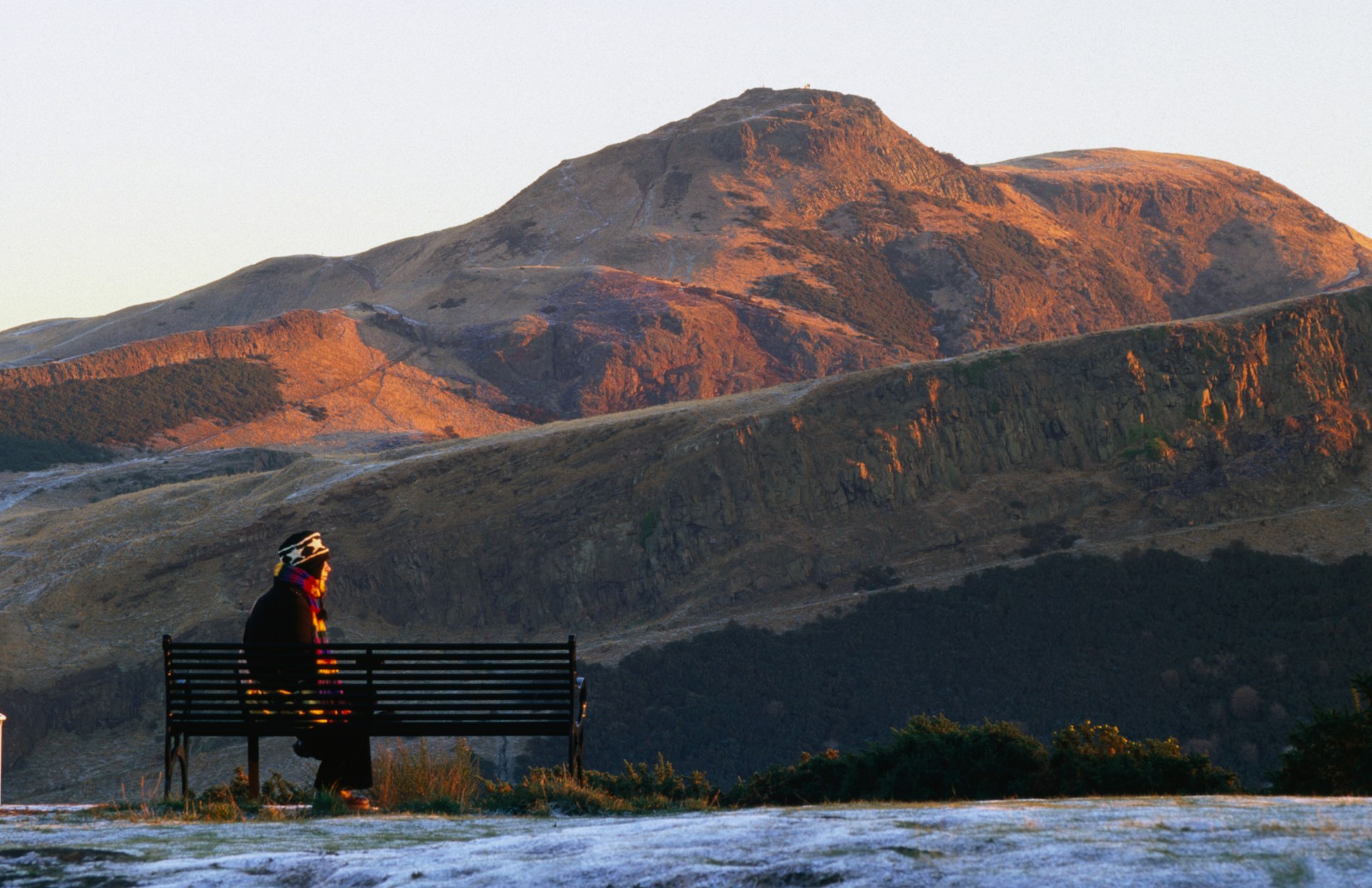 Man looking at Hollyrood Park and Arthur's Seat from Calton Hill with snow