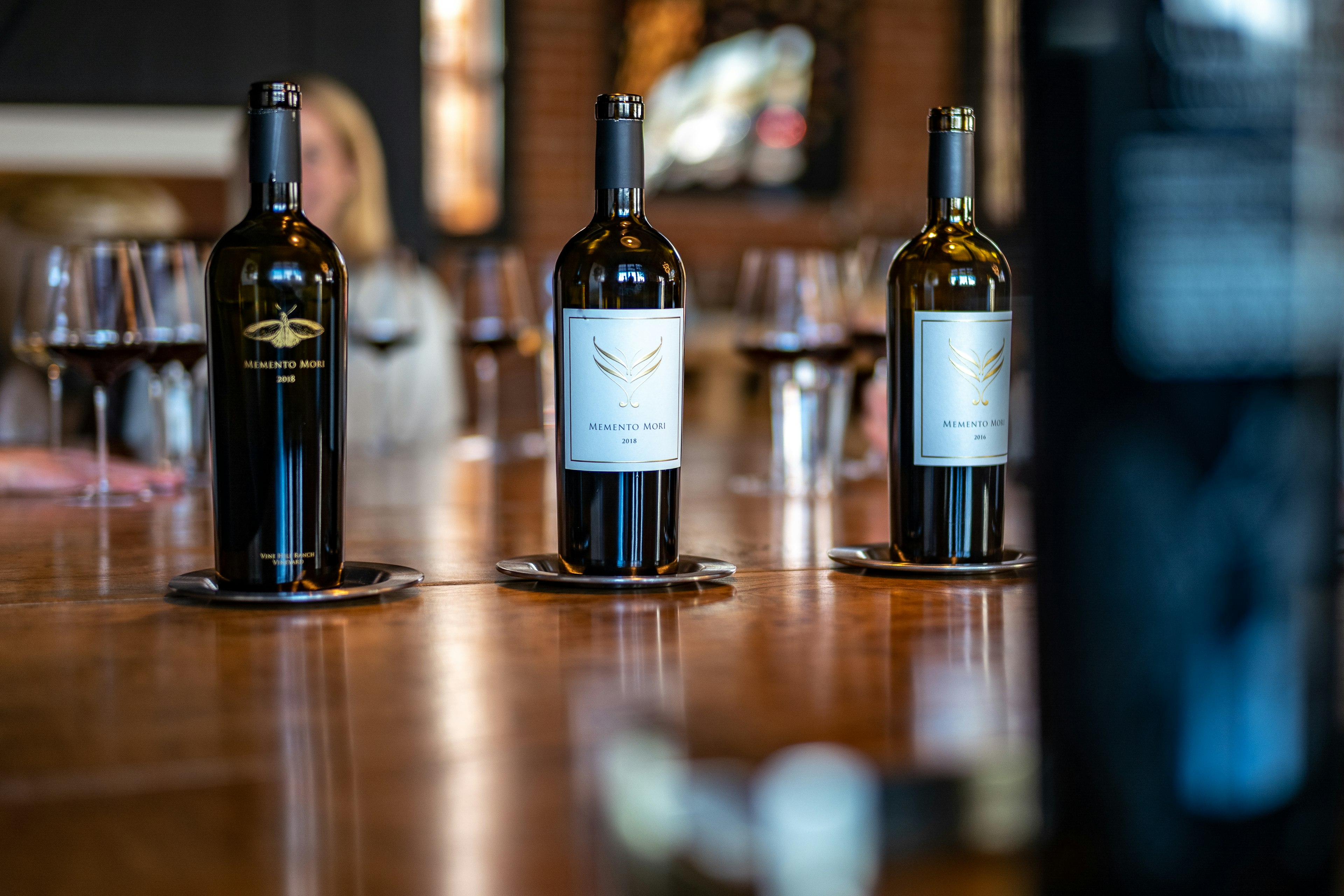 Three bottles of red wine standing on a dark wood table