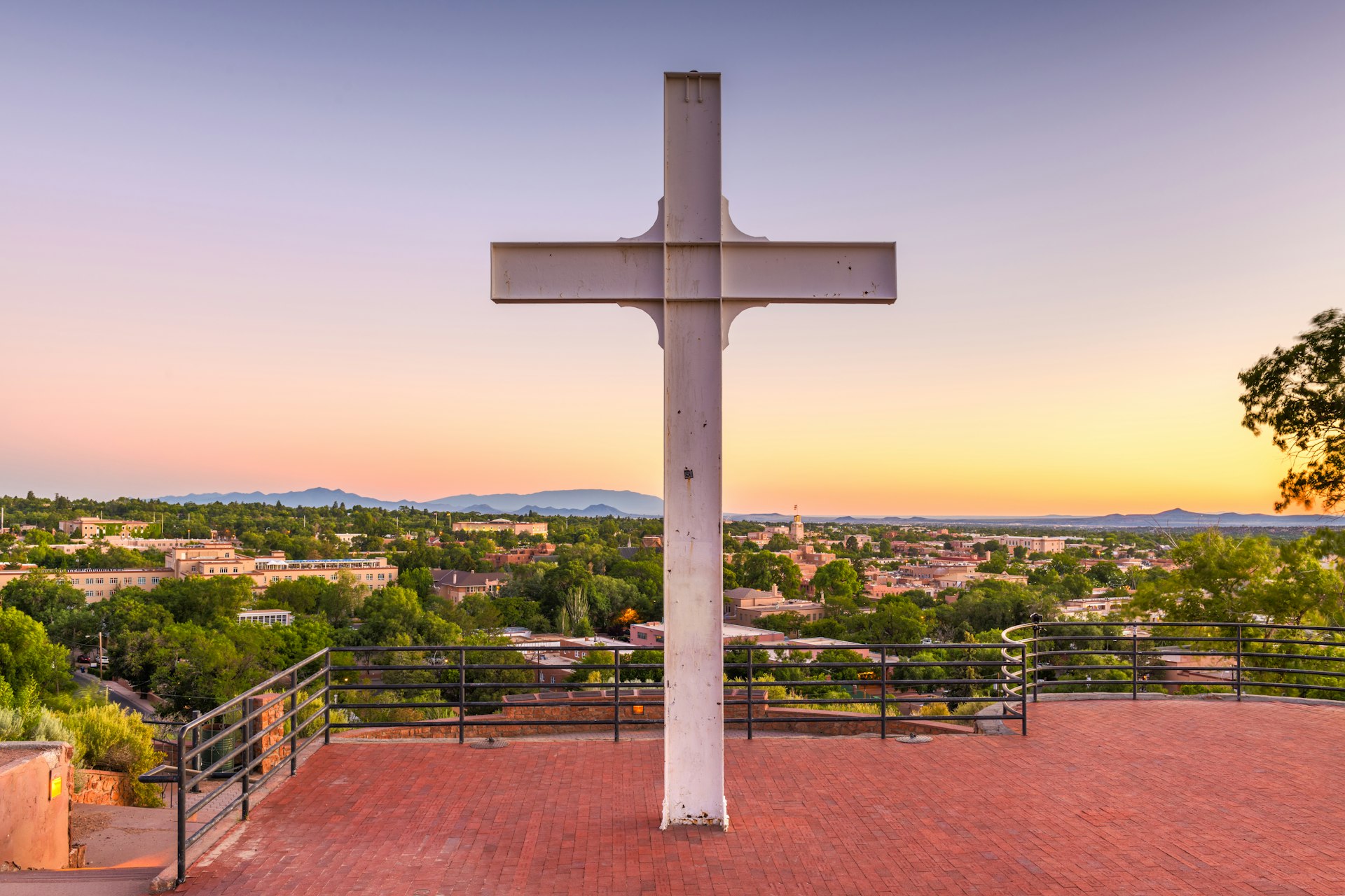 A view of the Cross of the Martyrs in Santa Fe: a large cross standing on a hill, with a view of the city skyline beyond it.