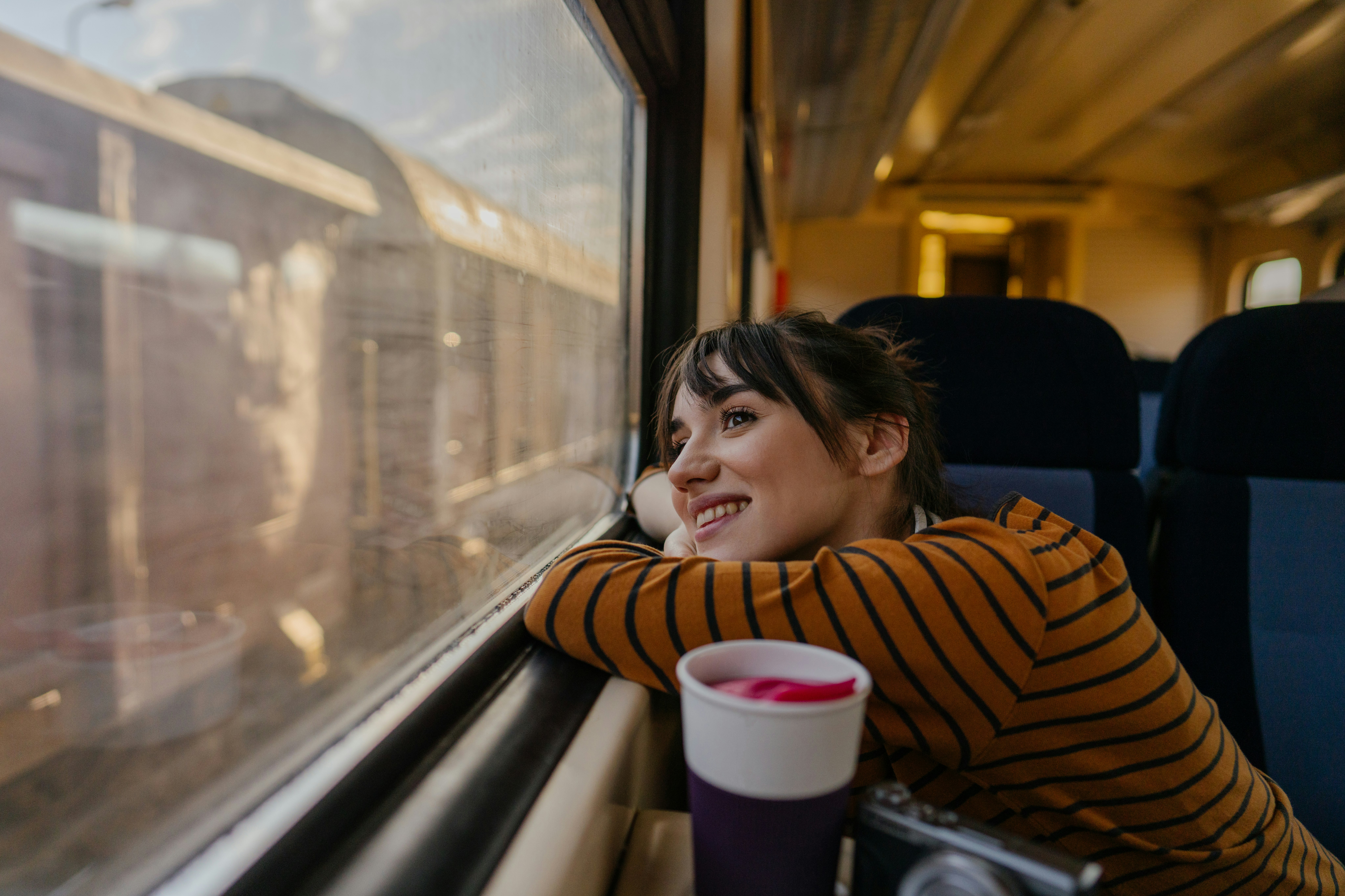 Photo of a young woman riding on a train, enjoying her trip while looking through the window in Serbia