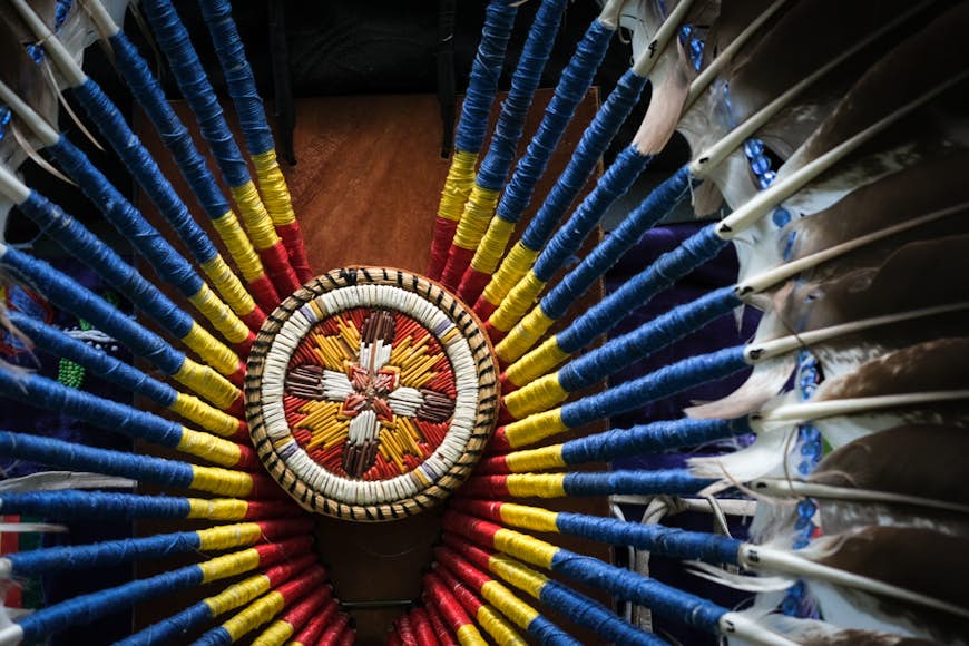 Un gros plan d'une partie d'un costume de cérémonie des Premières Nations avec des plumes et des broderies rouges, bleues, jaunes et blanches, Wendake, Québec, Canada