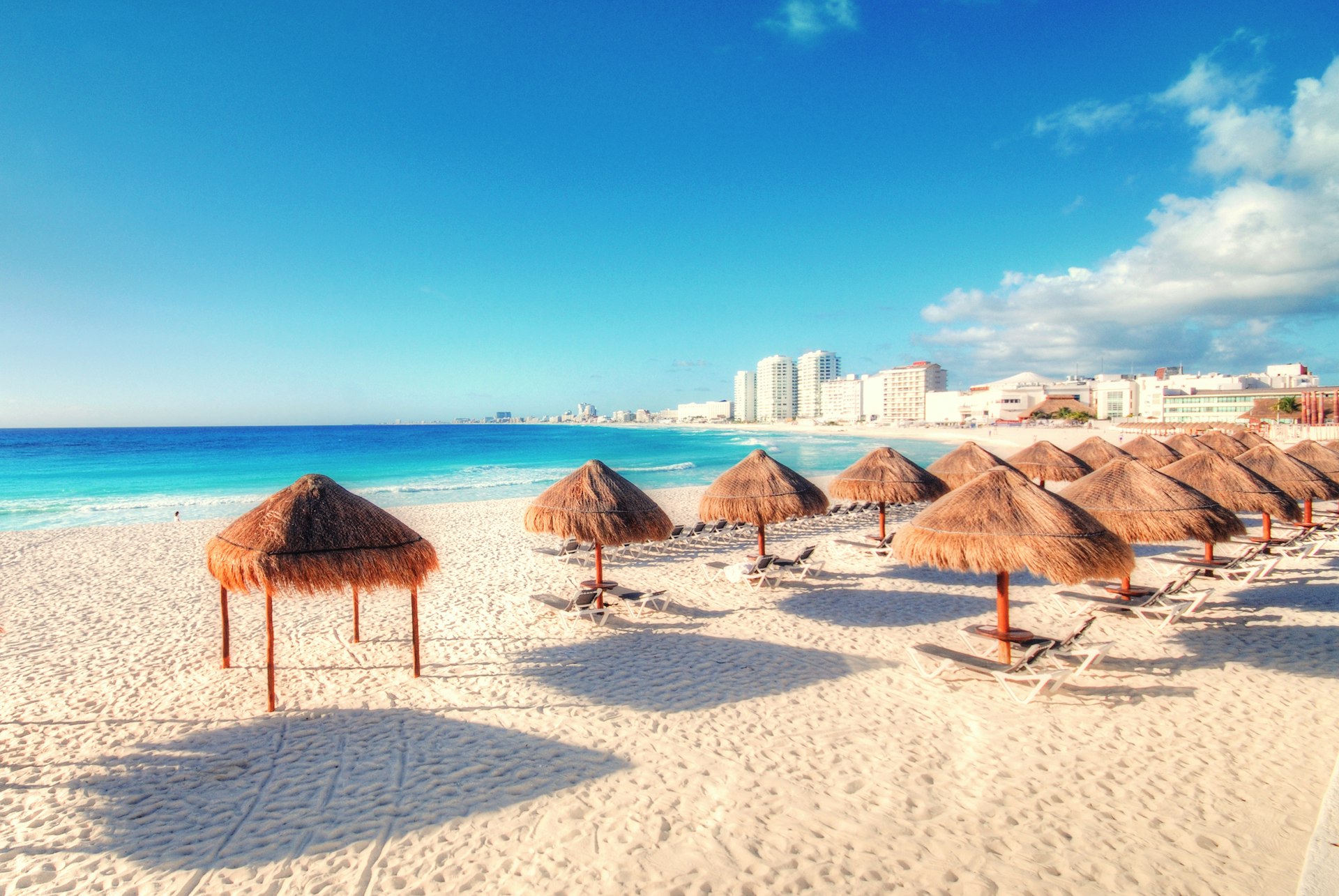 Rows of parasols and loungers on an empty beach in Cancun