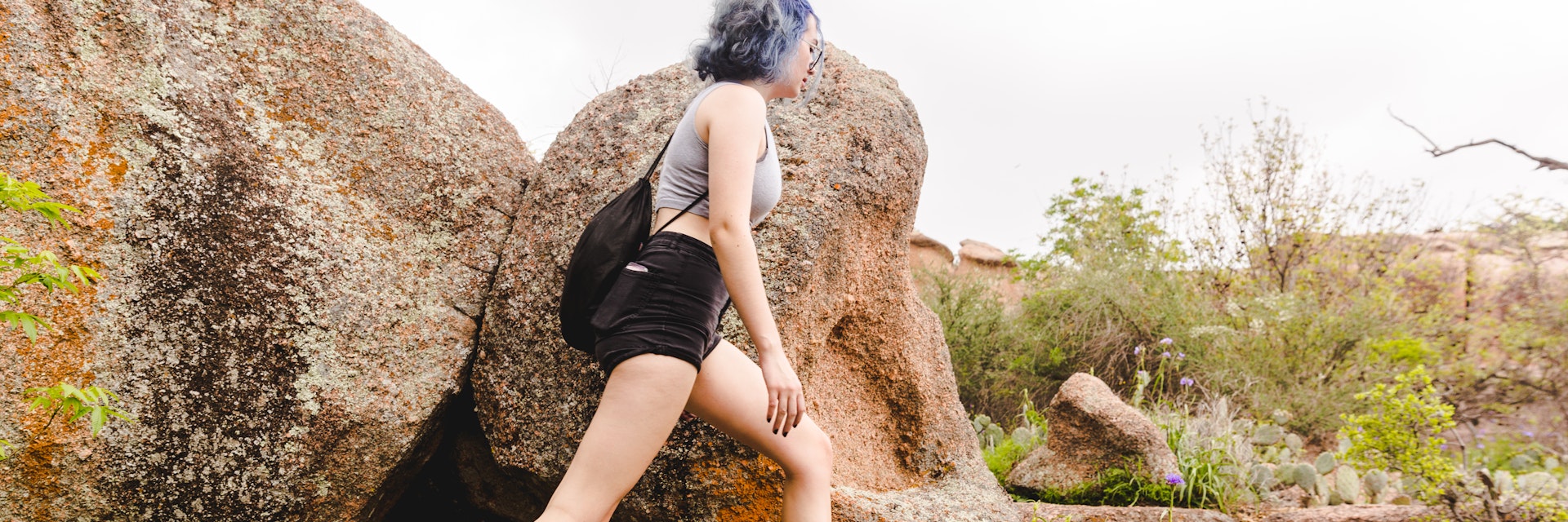 Enchanted Rock State Natural Area, Texas - Teenage Girl with blue hair, hiking on large granite boulders in a state park, isolated from people due to covid 19 social distancing regulations