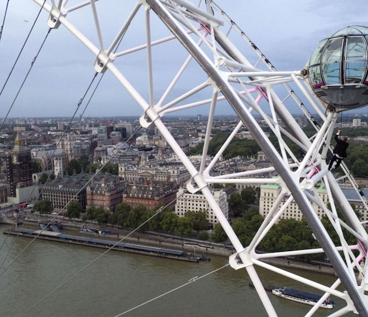 A man dressed as Britain's most famous secret service agent, James Bond, is silhouetted against the London skyline as he climbs the outside of a pod on the lastminute.com London Eye, the landmark tourist attraction in central London, ahead of the world premiere of No Time To Die, the latest instalment in the Bond franchise. Picture date: Tuesday September 28, 2021. (Photo by Steve Parsons/PA Images via Getty Images)