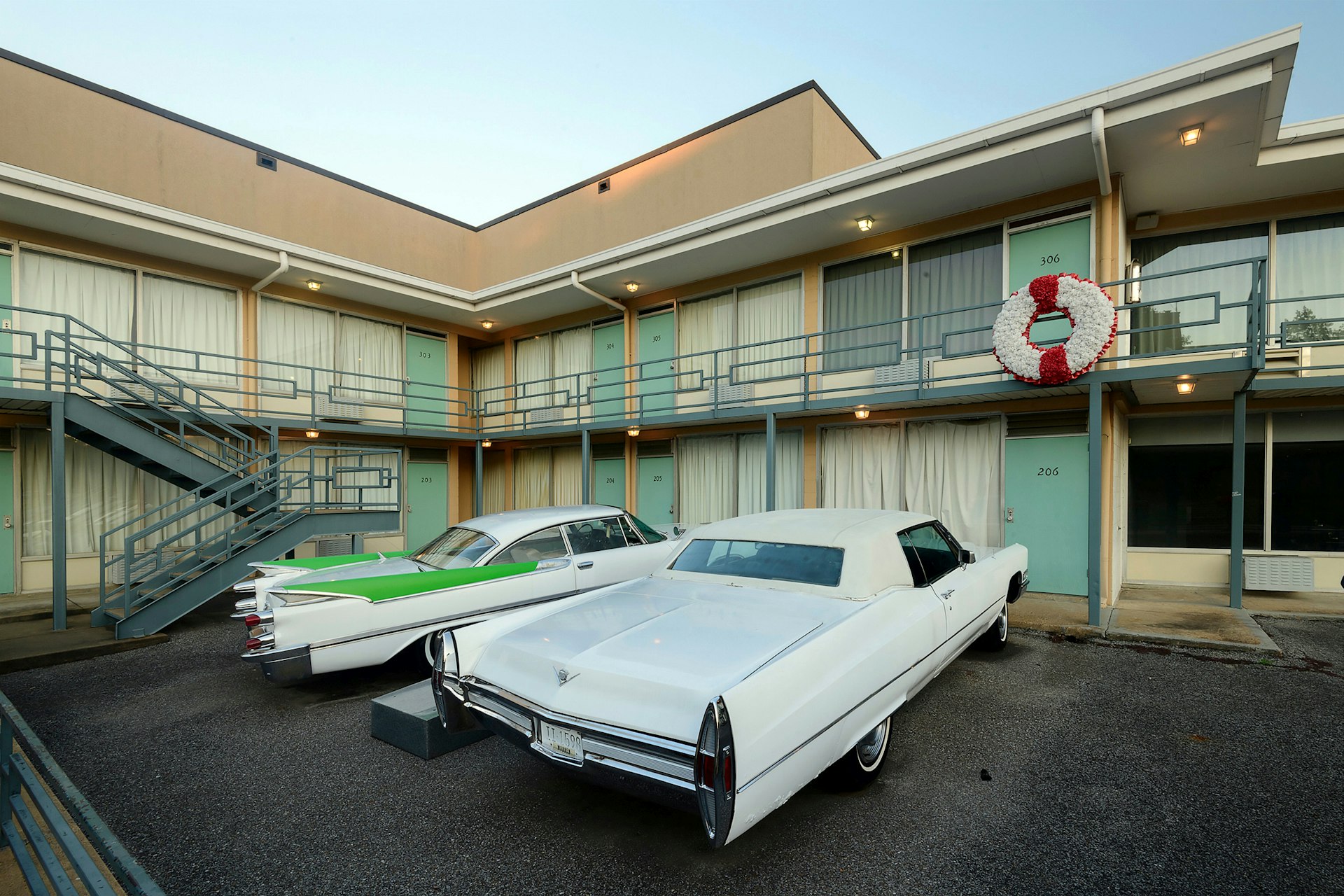 A pair of Cadillacs, one all white and the other white with green fins, are parked outside the balcony of the Lorraine Motel. The scene where Dr. Martin Luther King Jr. was assassinated.   
