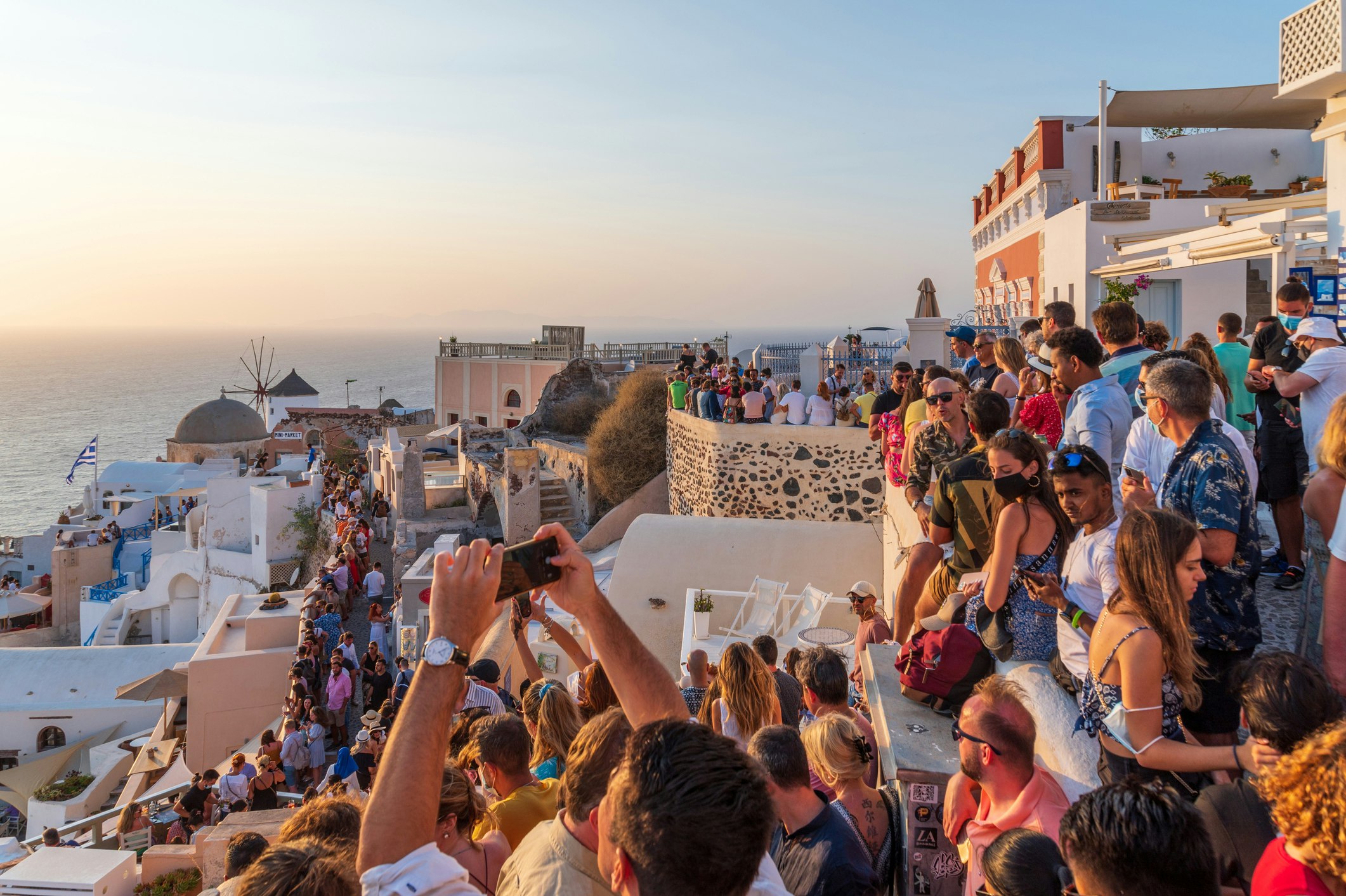 Tourists watching and taking pictures of the sunset in Oia, Santorini, Greece