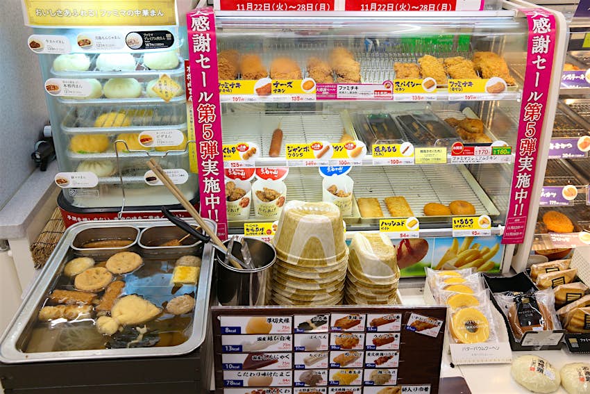 Fast food items (nikuman steamed buns, oden broth winter foods and fried meats) on display at a Japanese convenience store in Tokyo.